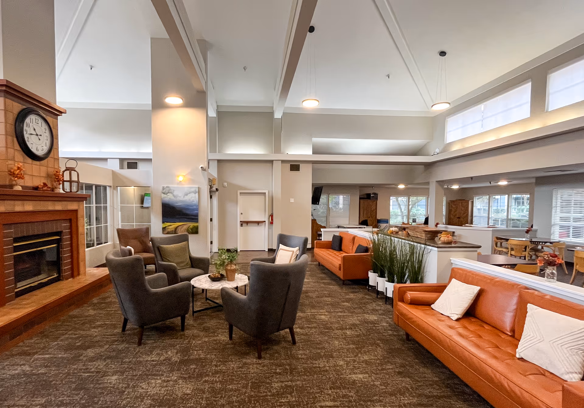 Spacious Carlton Senior Living Concord lounge with sofas, chairs, fireplace, and plants.