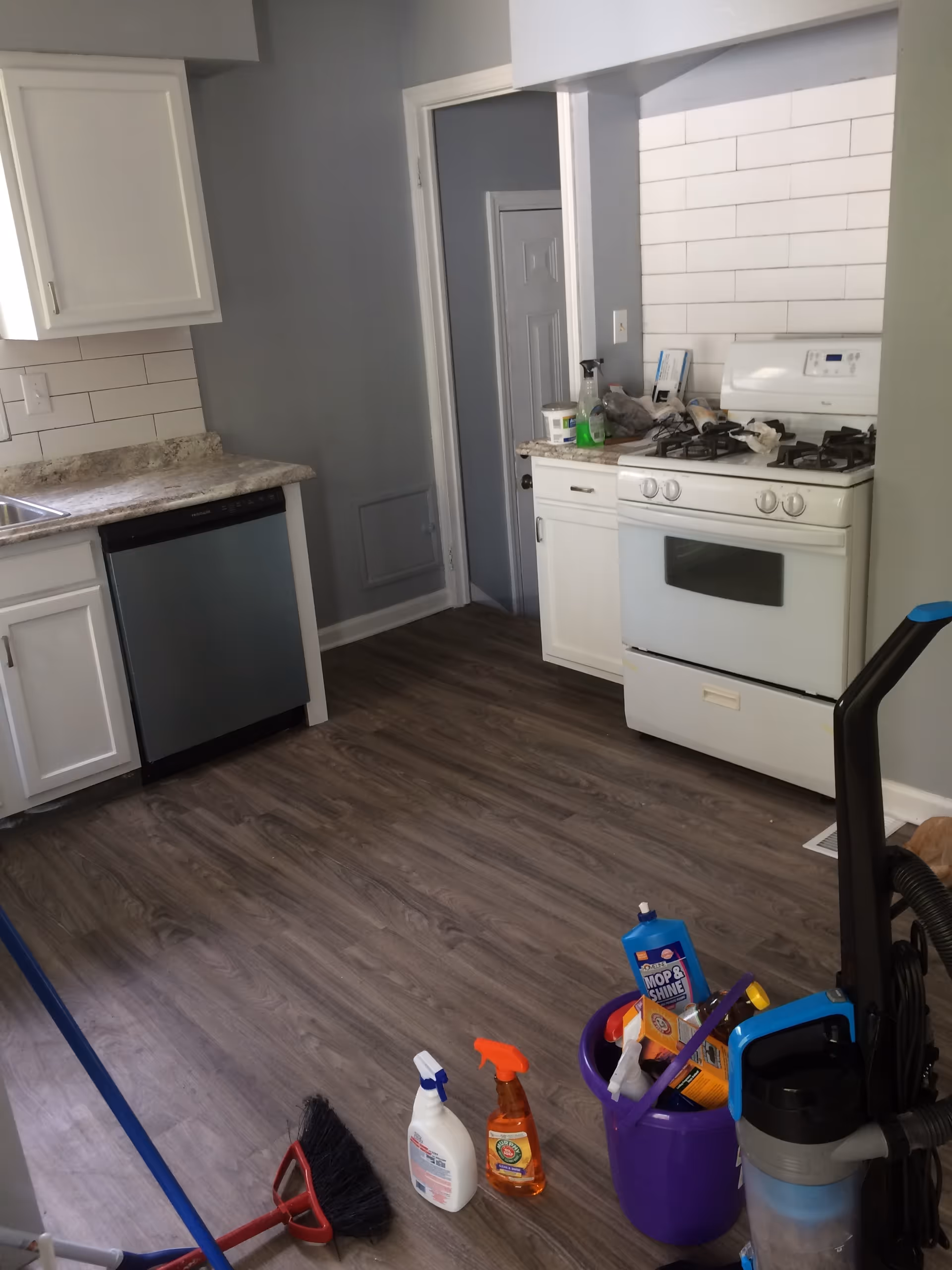 Small kitchen in a senior living facility with stove, dishwasher, and cleaning supplies.