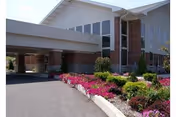 Front of a Goodwill Retirement Community building with driveway and vibrant flower beds.