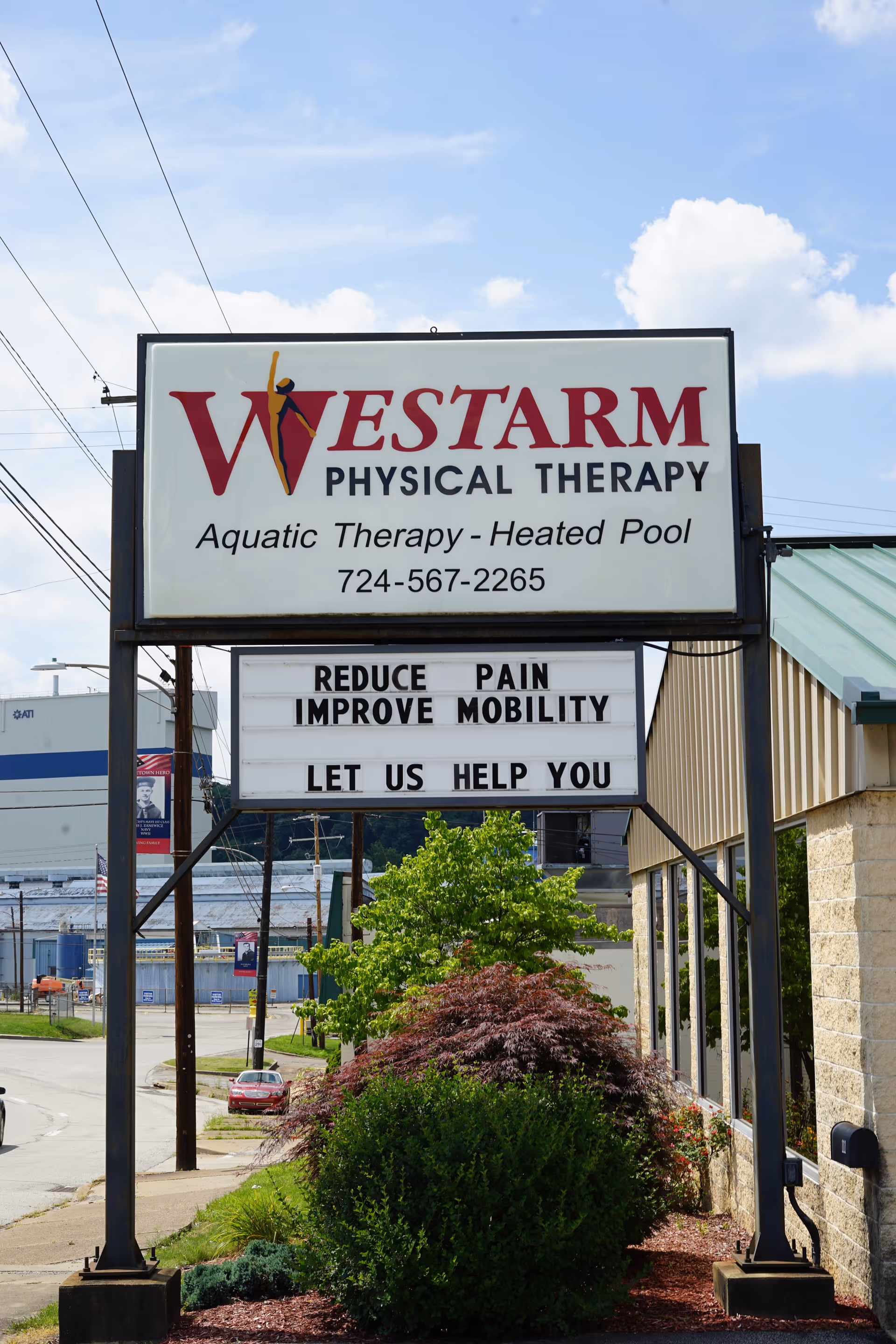 Large outdoor sign for WESTARM Physical Therapy with aquatic therapy text, landscaping, and building facade.