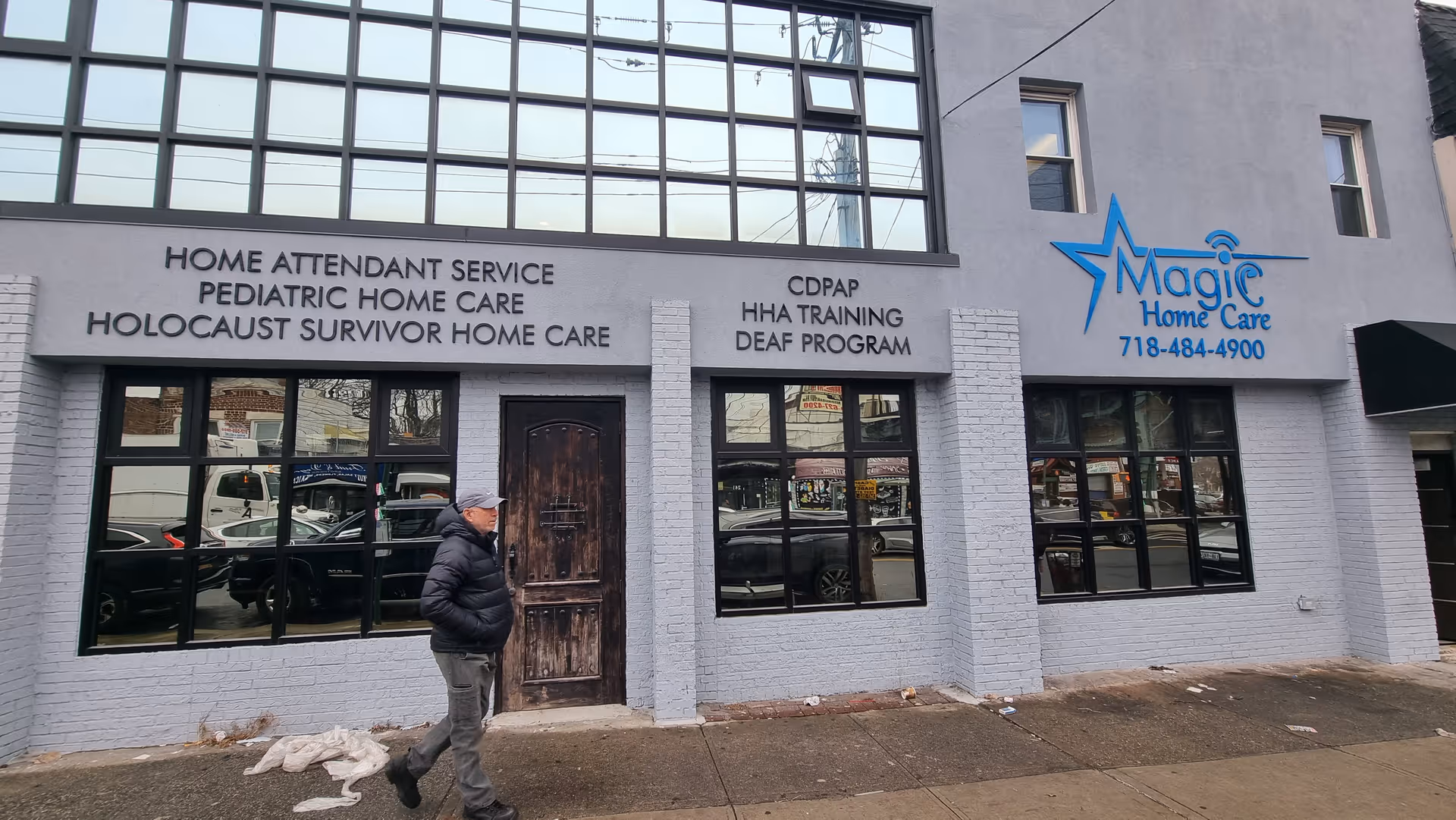 Exterior view of a light-gray building with Magic Home Care signage and a man walking outside
