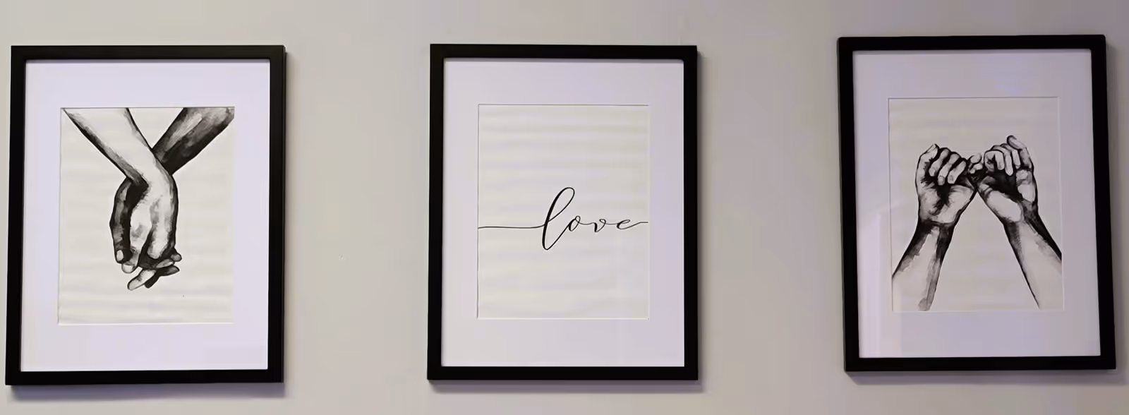 Three black-and-white framed prints hang in a row on a light wall.