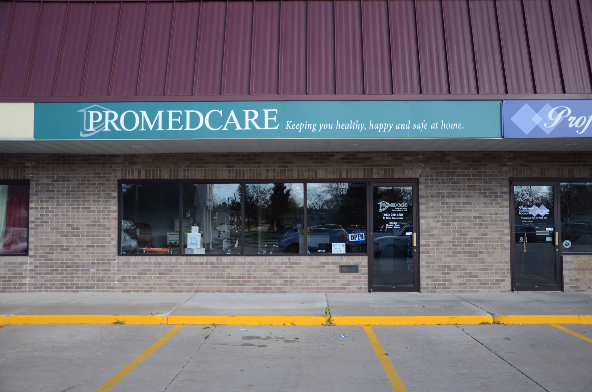 Brick storefront with Promedcare sign and glass doors, parking lot in front.