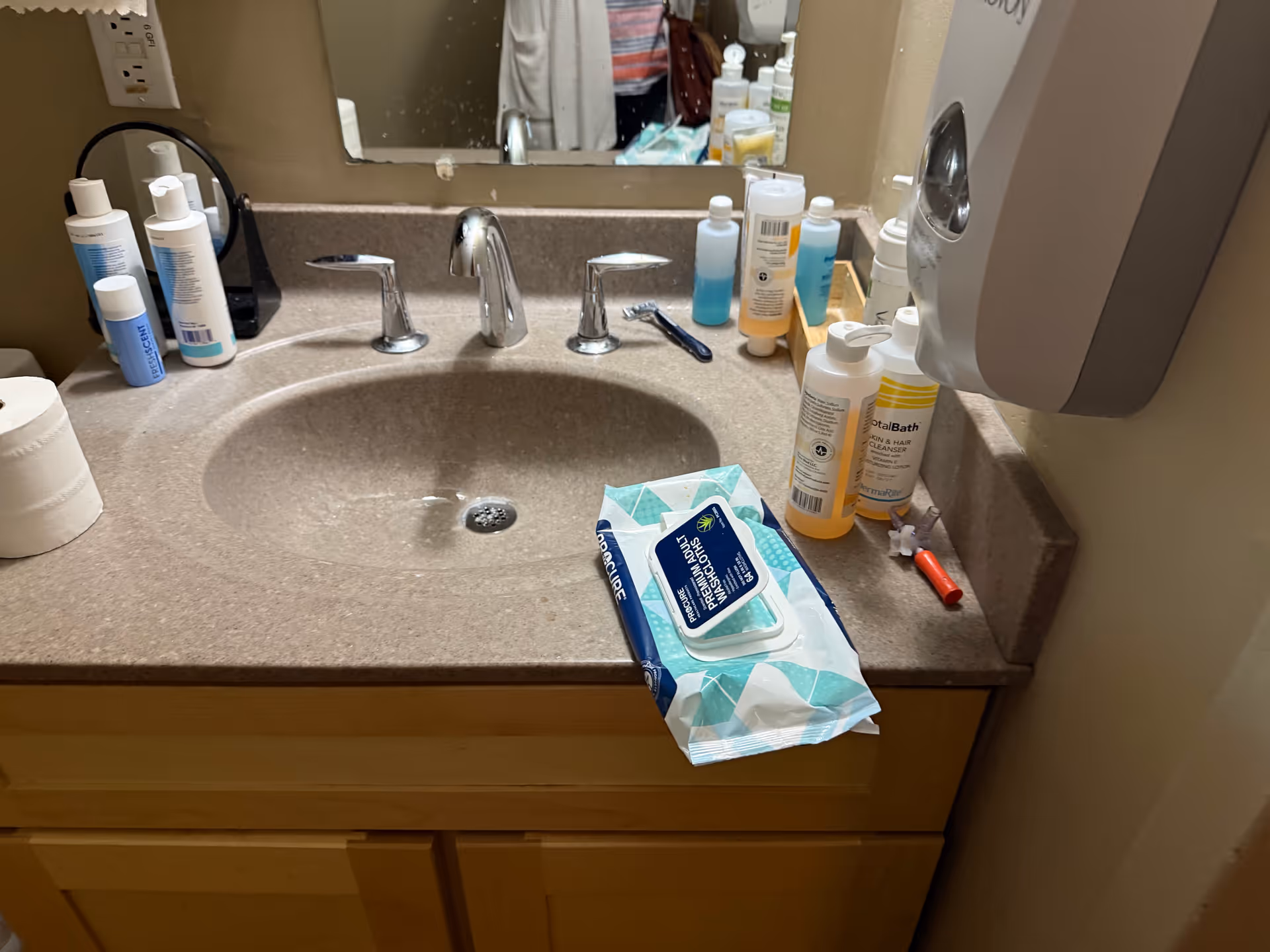 Bathroom sink with toiletries, tissues, and sanitizer on the counter.