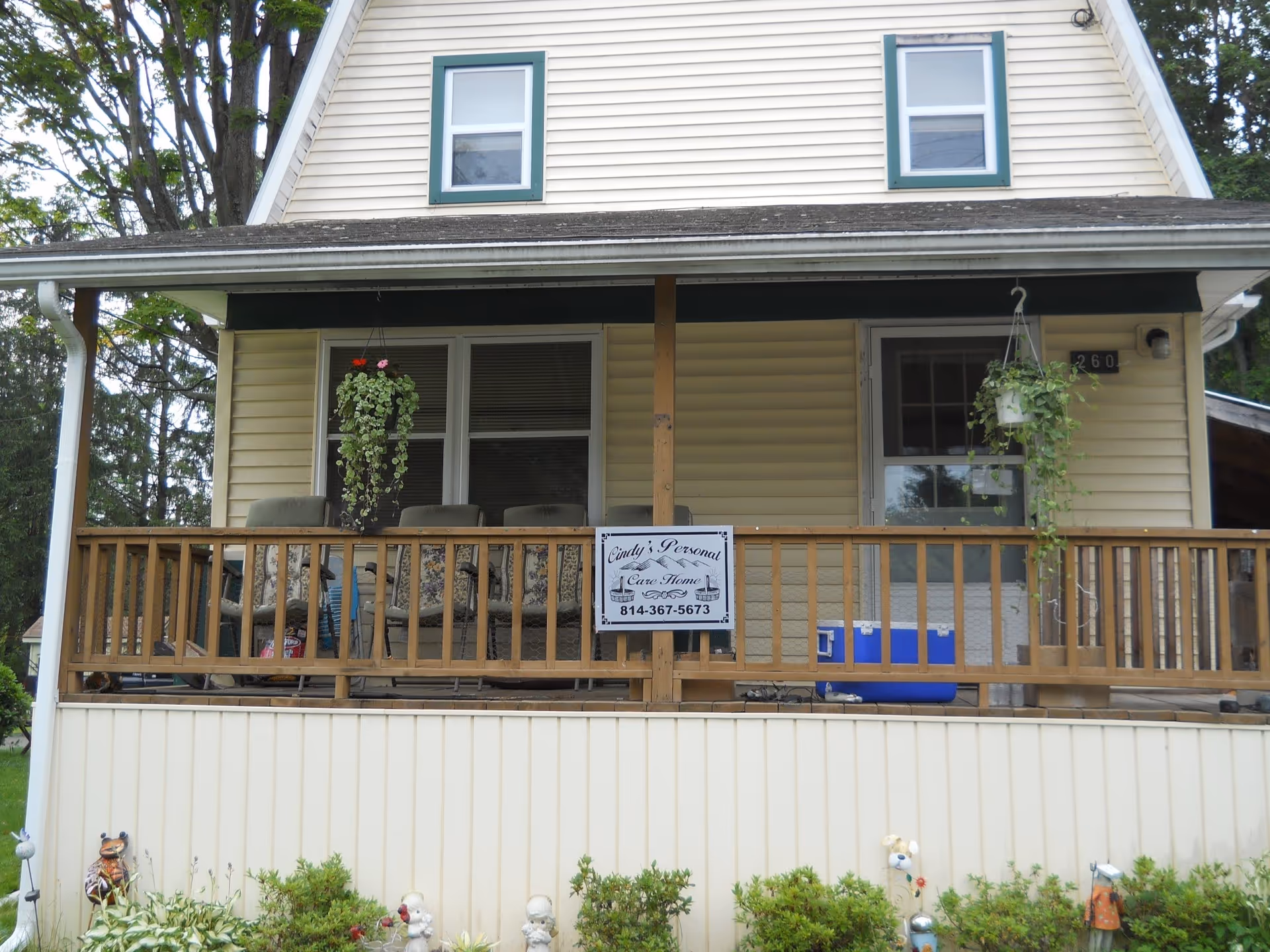 Front view of a yellow house with a wooden porch and Cindy's Personal Care Home sign