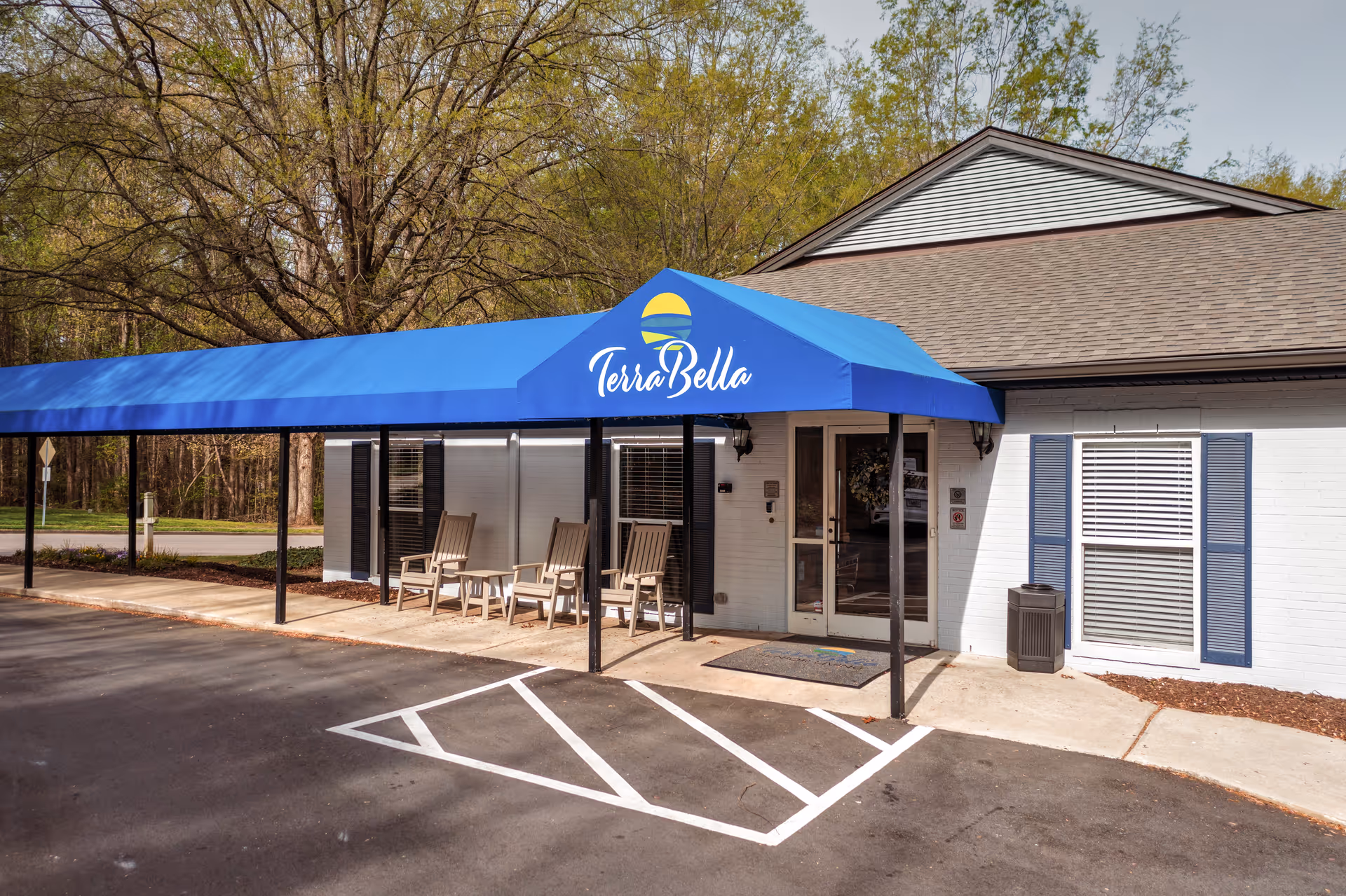Exterior view of TerraBella Northridge entrance with a blue canopy and four chairs outside.