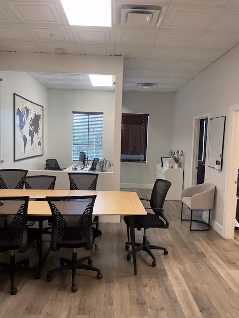 Office-style common area with tables, chairs, a world map, and plants.