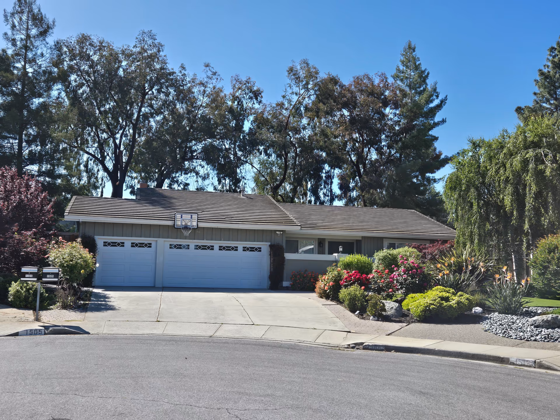 Single-story suburban home with three-car garage and landscaped front yard along a quiet street.
