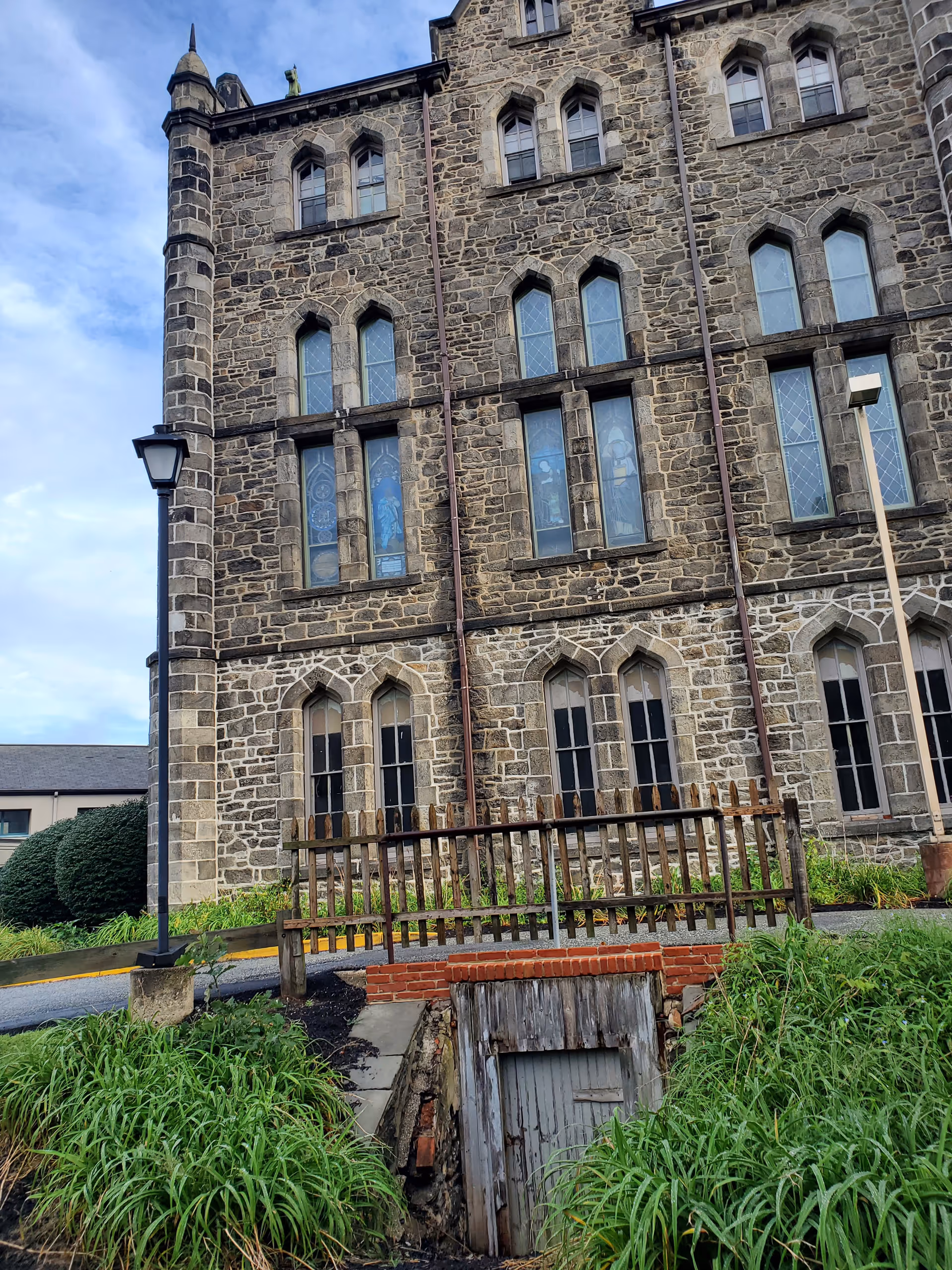 Historic stone building with tall arched windows and a wooden front railing.