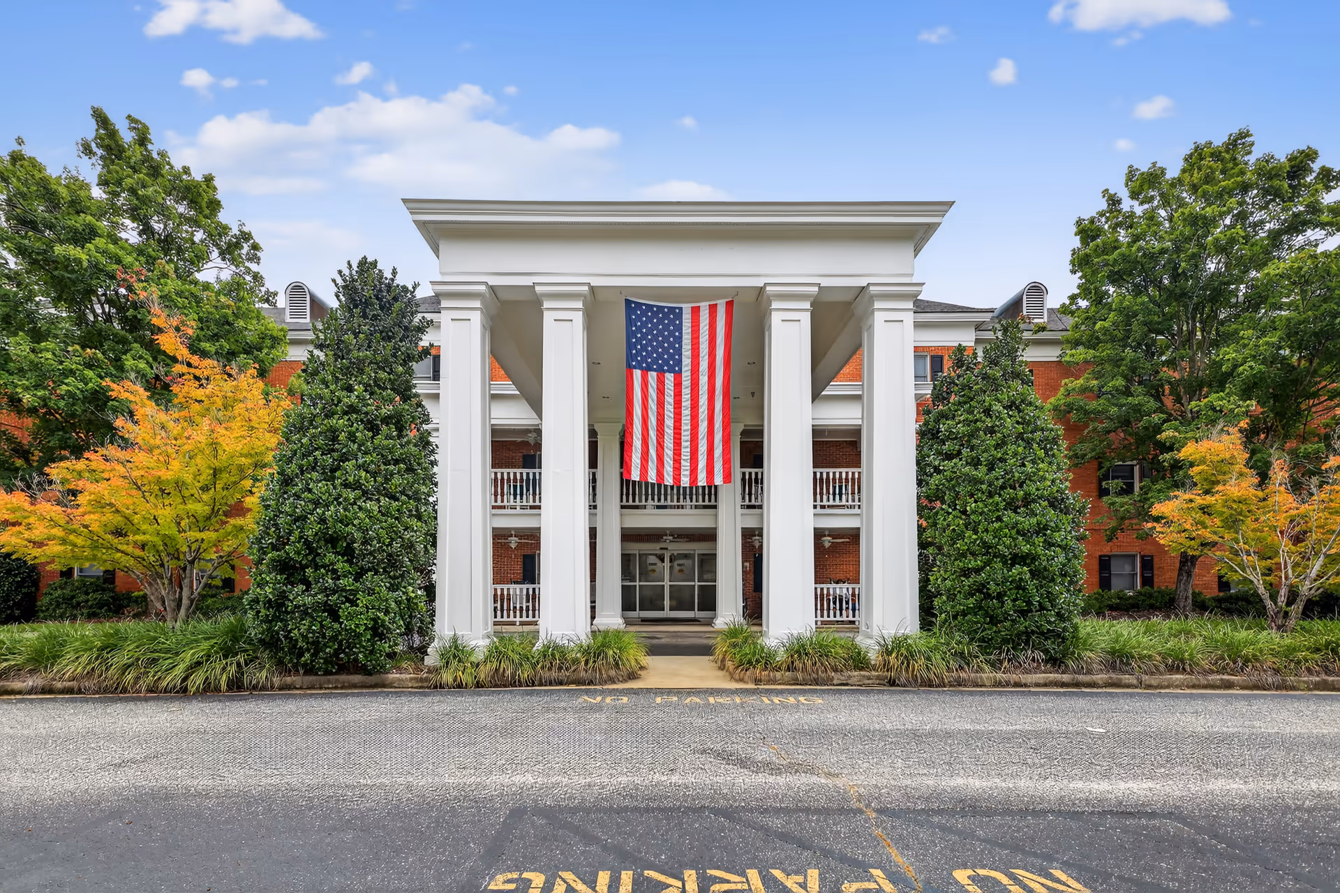 Exterior view of Covenant Place with white columns, flag, brick building, and trees.