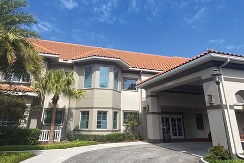 Sunny exterior of The Windsor at San Pablo, a beige senior living building with red roof