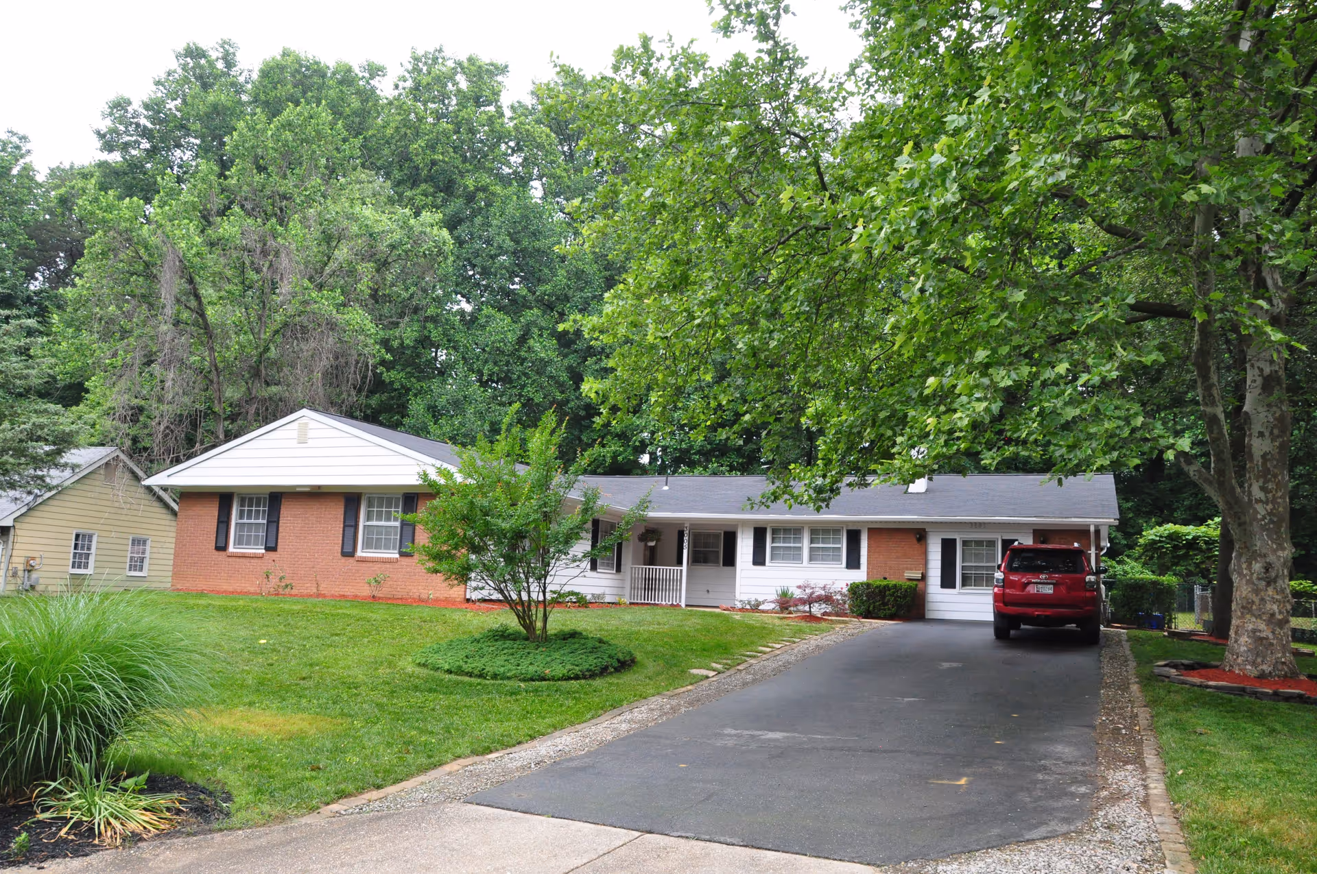 Single-story brick assisted living building with driveway, parked car, and green lawn.