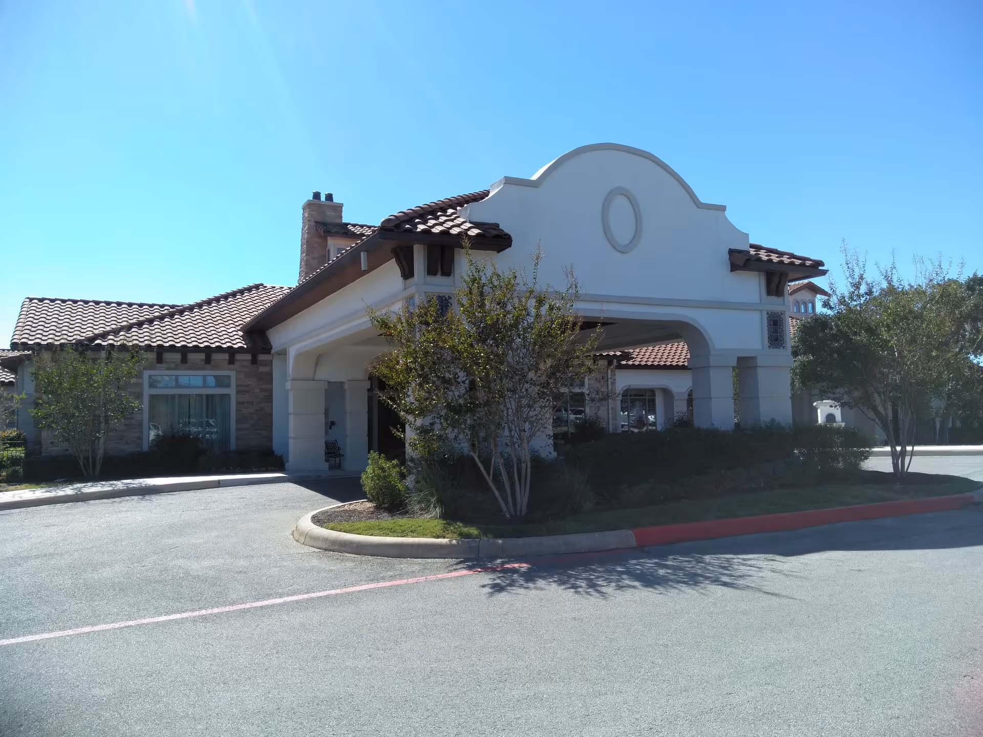 Exterior view of a senior living facility entrance with a white curved façade.
