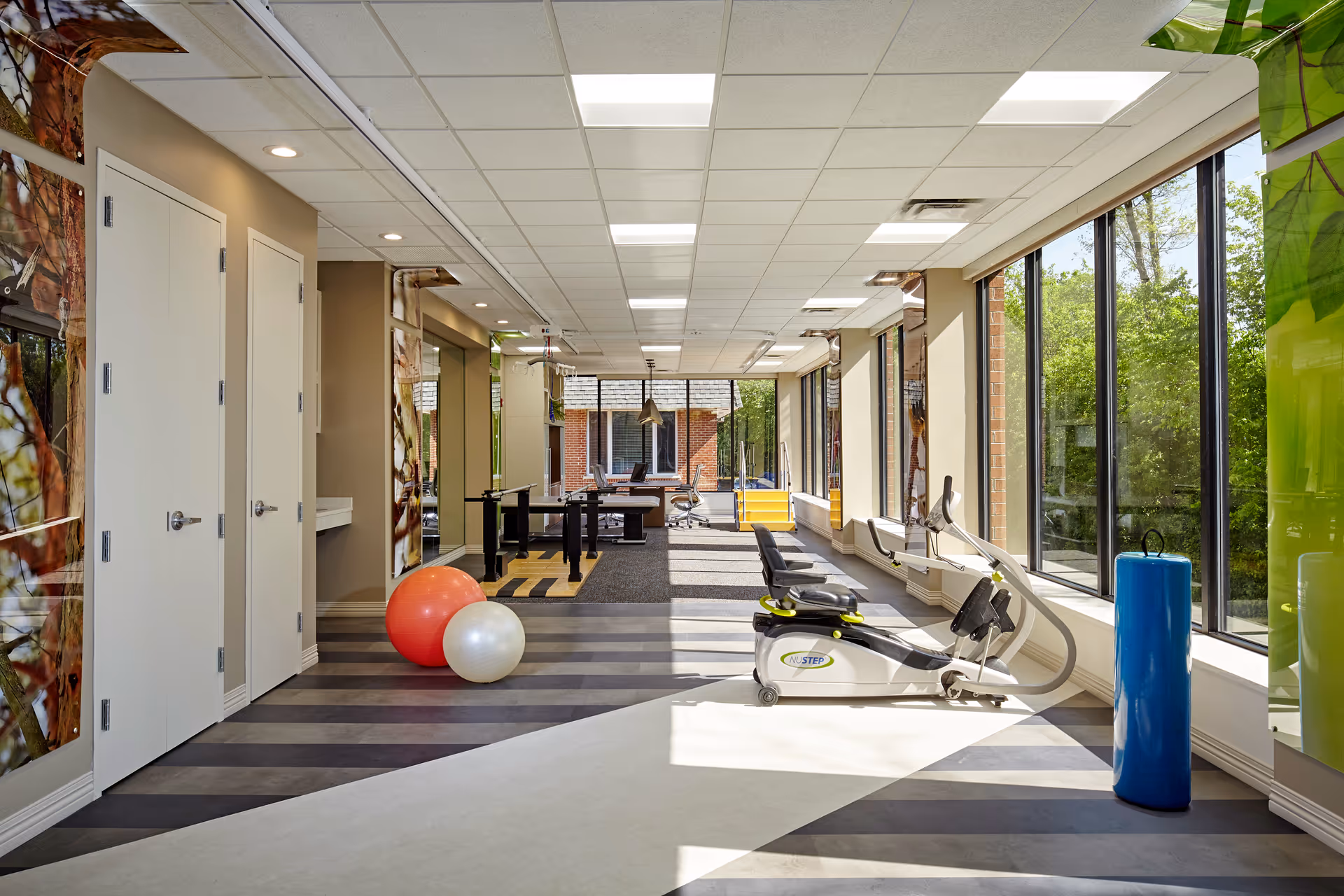 Bright Alta Rehab gym at Oak Brook with exercise bikes, balls, and large windows.