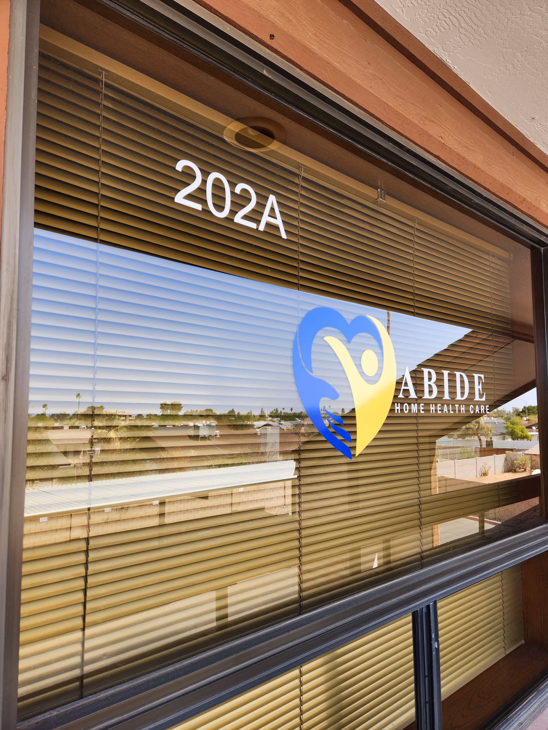 Exterior storefront window with blinds displaying Abide Home Health Care logo and 202A