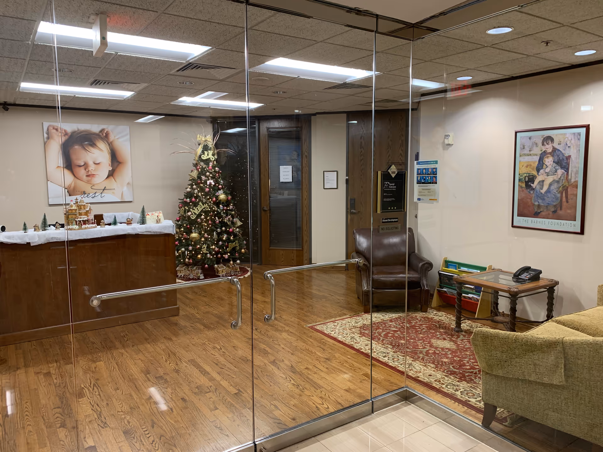 Glass-walled facility lobby with Christmas tree, reception counter, seating area, and wall art.