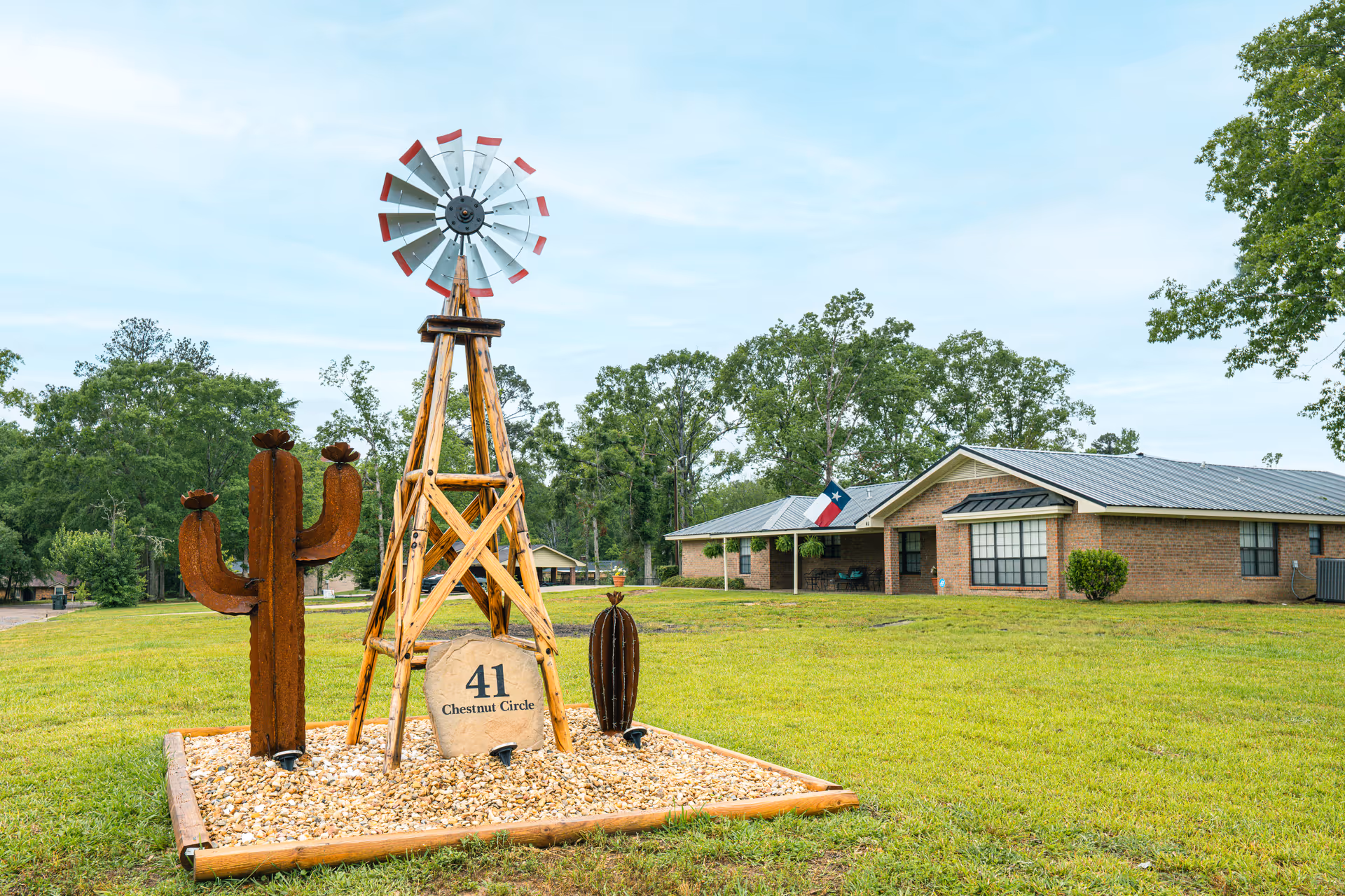 Outdoor view of Rosewood Assisted Living's brick building with windmill sculpture and cactus garden.