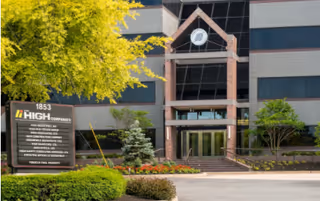 Exterior view of a building entrance with landscaping and a front sign.
