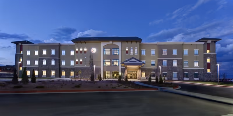 Front exterior of Center at Cordera, a modern senior living building at dusk.