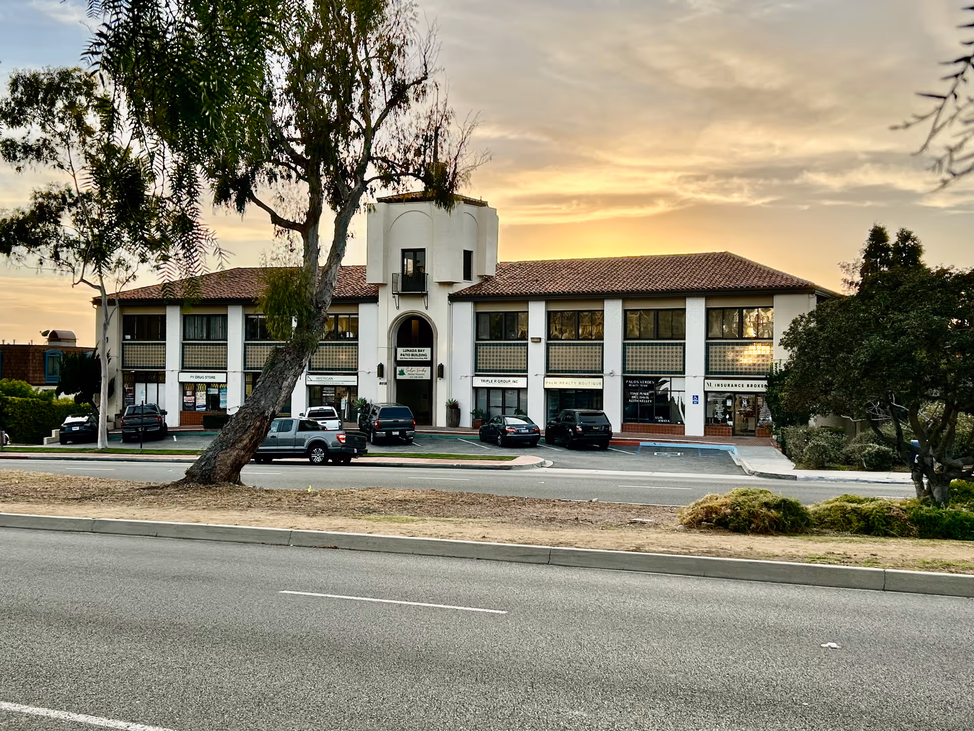 Exterior view of a two-story facility with a central tower and parked cars.