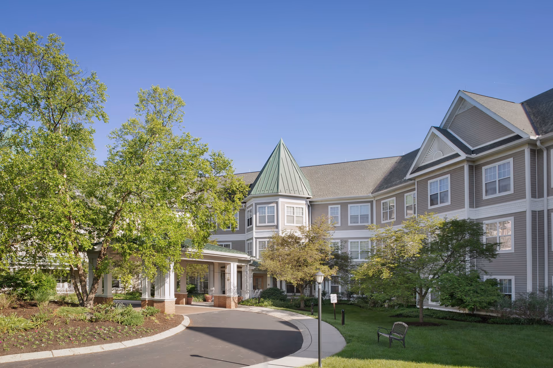 Sunrise of Abington exterior building with entrance, curved driveway, and surrounding trees.