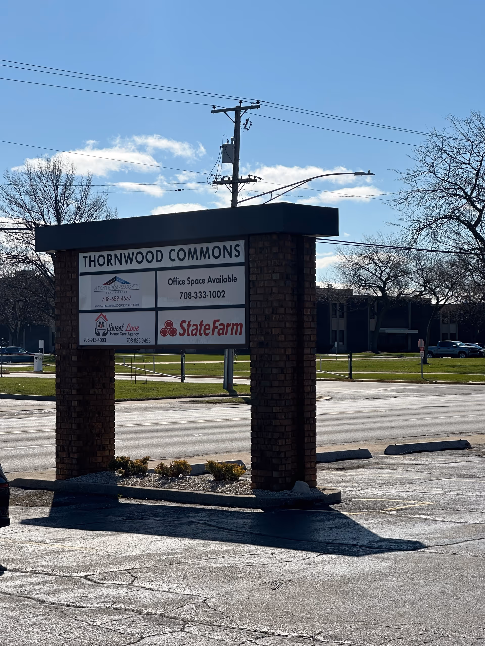 Outdoor brick sign for Thornwood Commons showing office ads, including Sweet Love Home Care Agency.