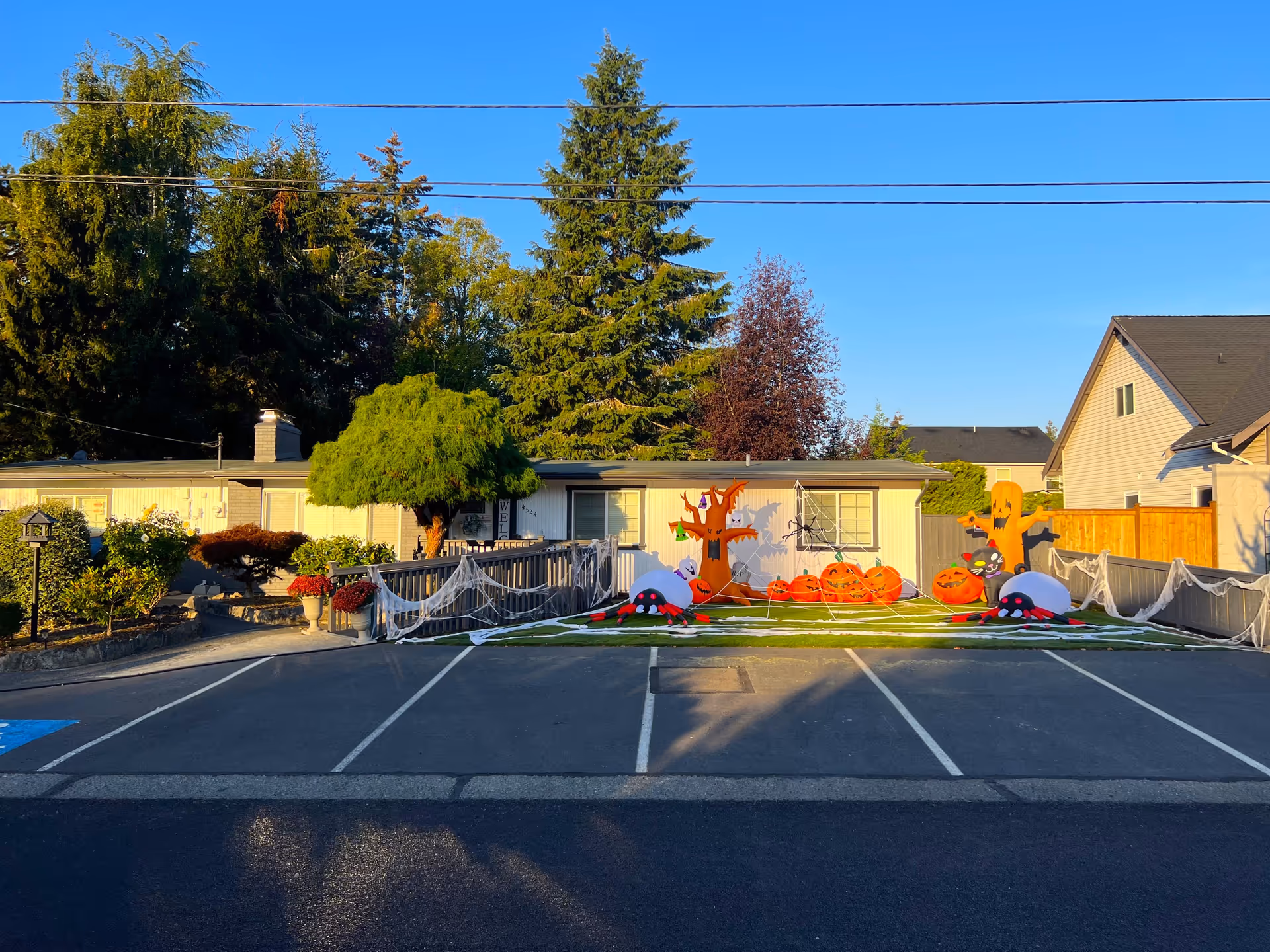 Front of a single-story senior care home with Halloween decorations on the lawn and empty parking spaces in front.
