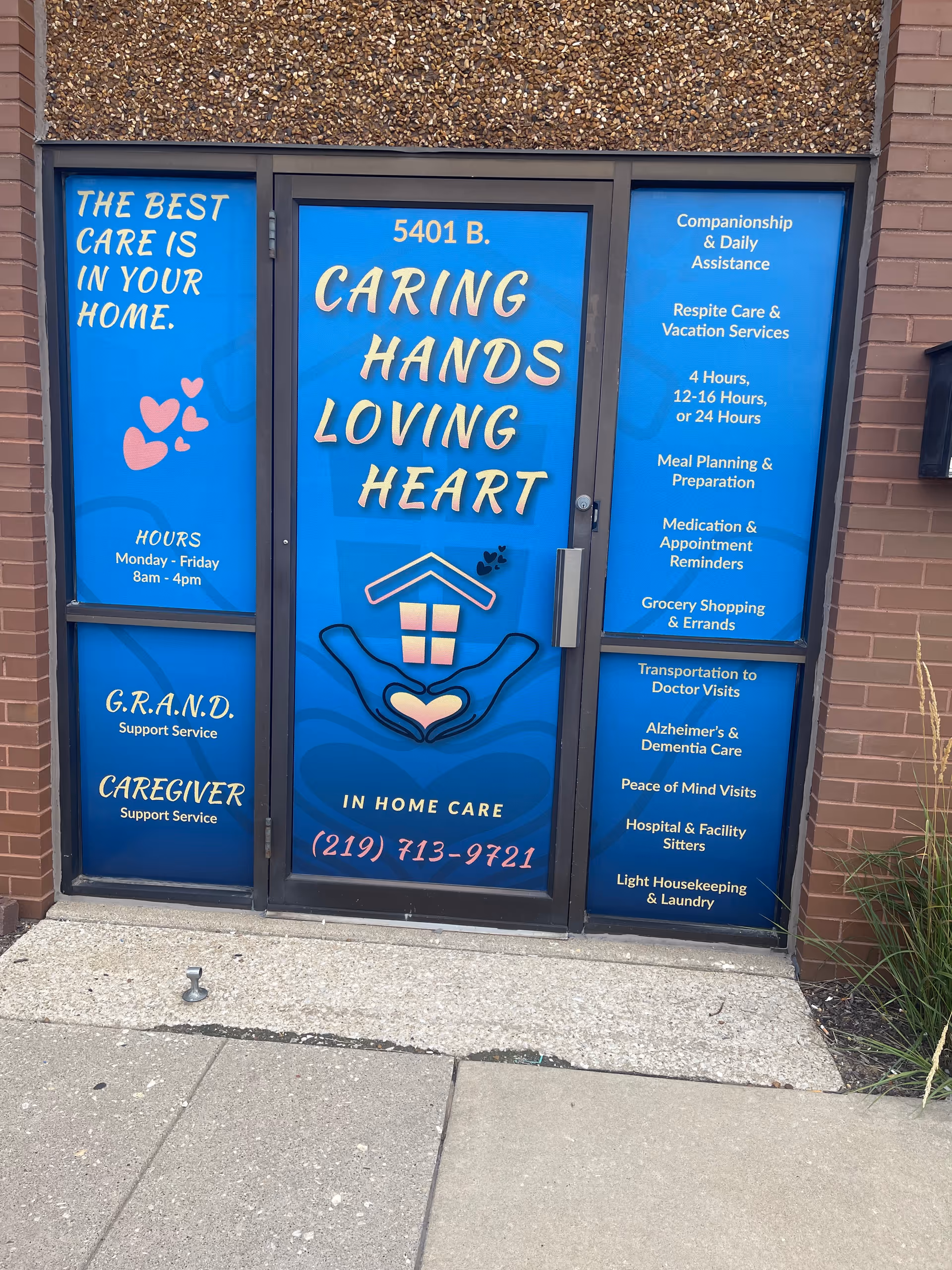 Blue storefront doors display Caring Hands Loving Heart in-home care signage.