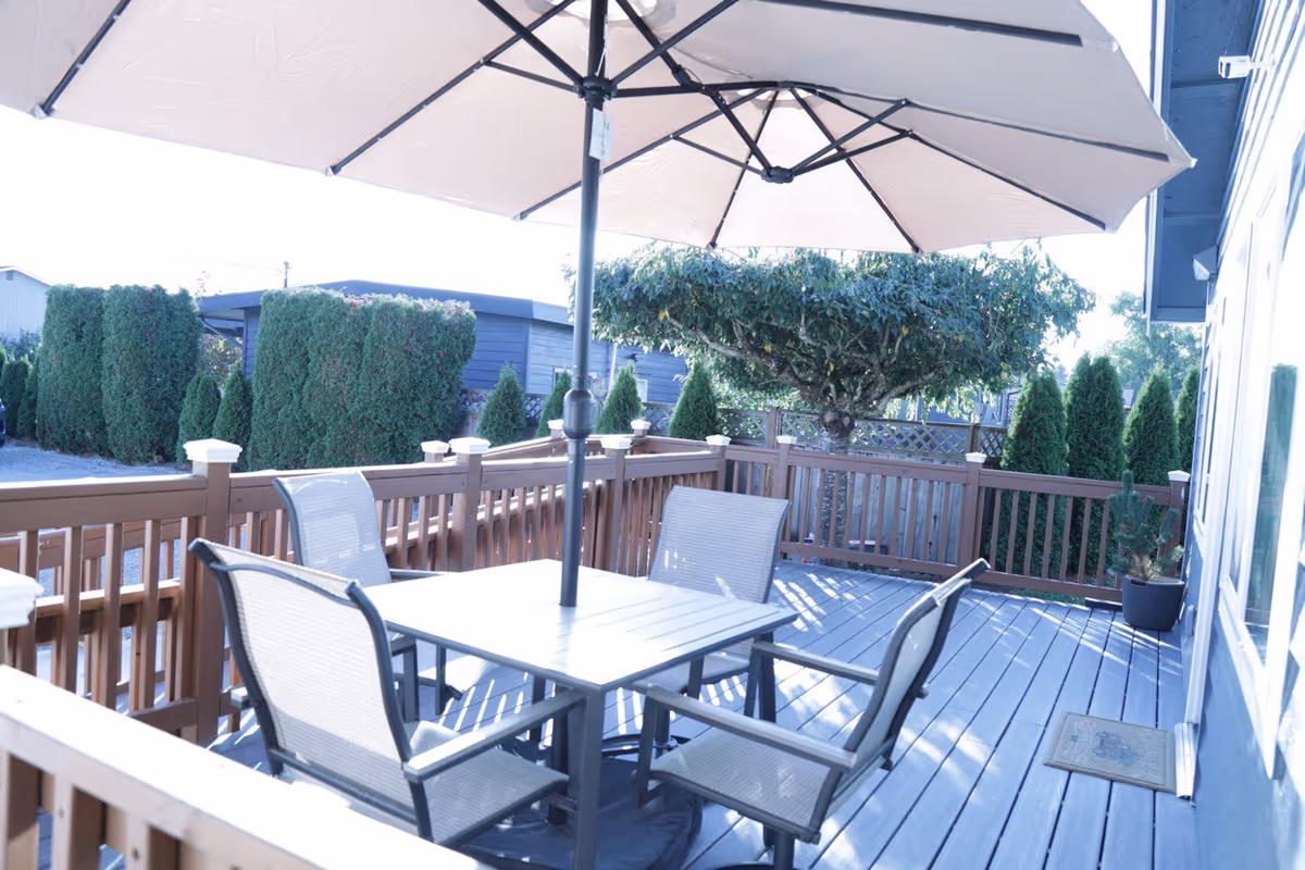 Outdoor wooden deck with seating, a table, and a large umbrella.