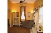 Cozy yellow living room with sofa, chairs, and floor lamps in a senior facility.