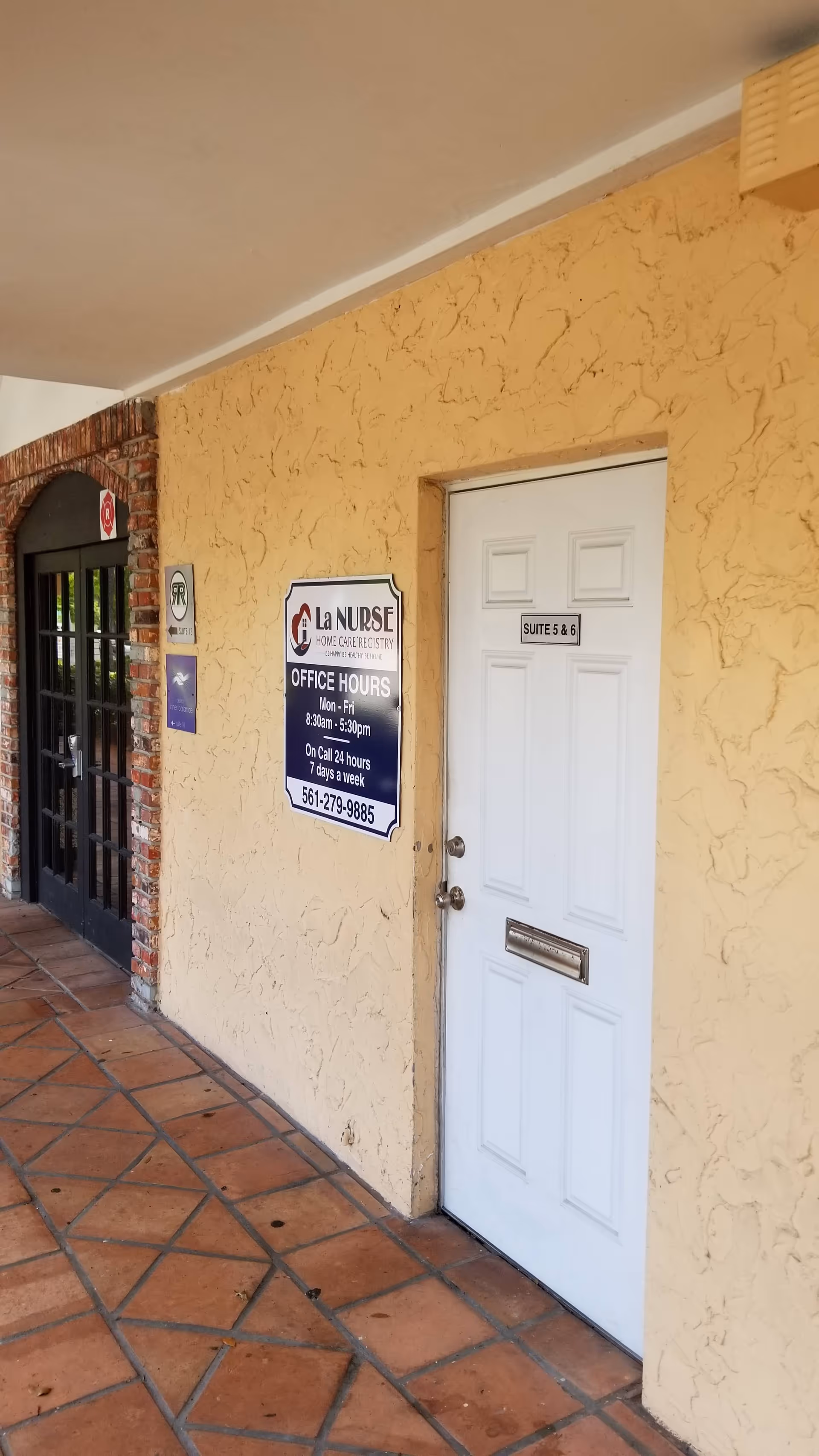 Exterior view of a stucco walkway with a white door labeled Suite 5 & 6.