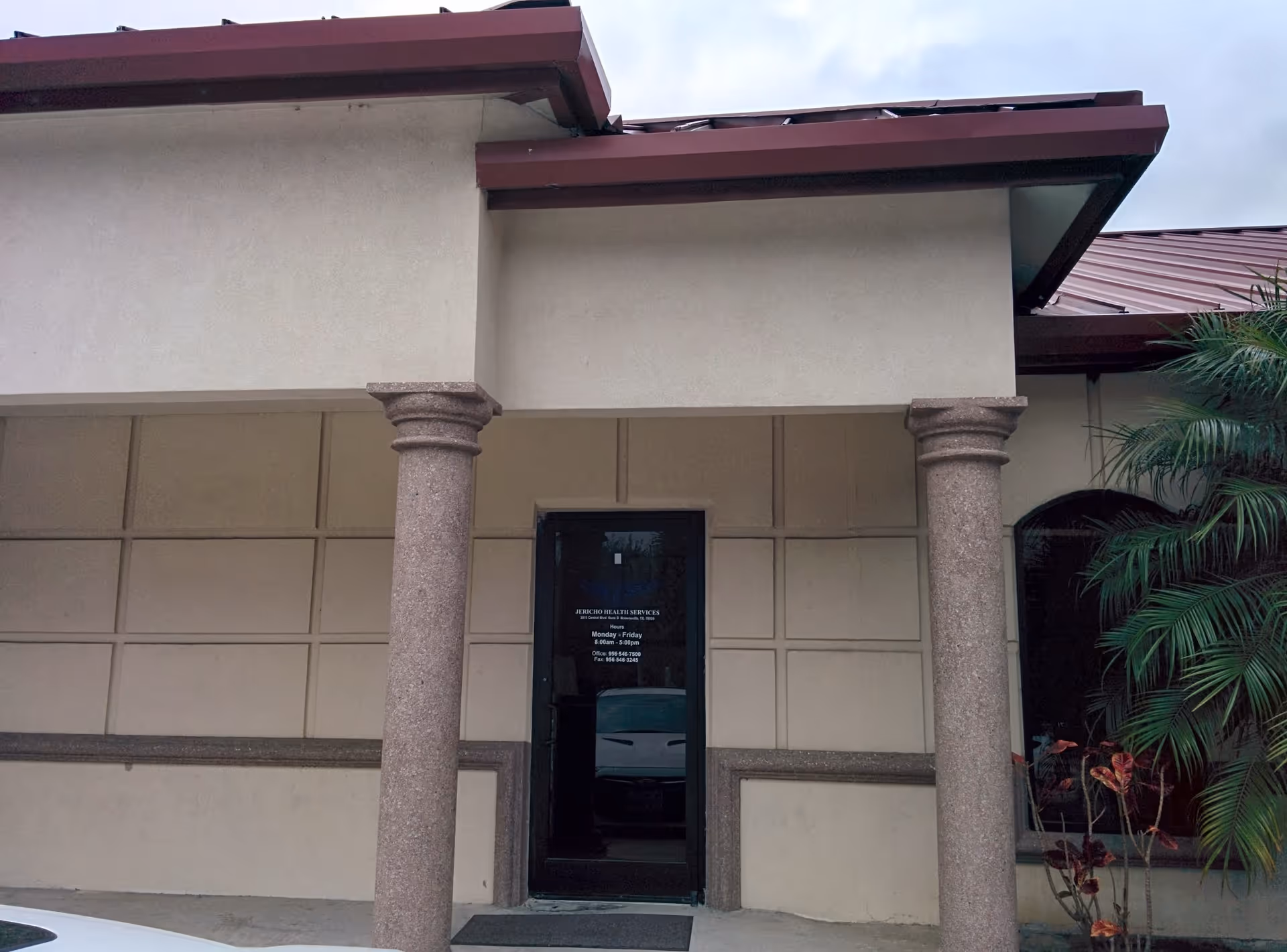 Entrance to Jericho Health Services building with beige walls, columns, and glass door.