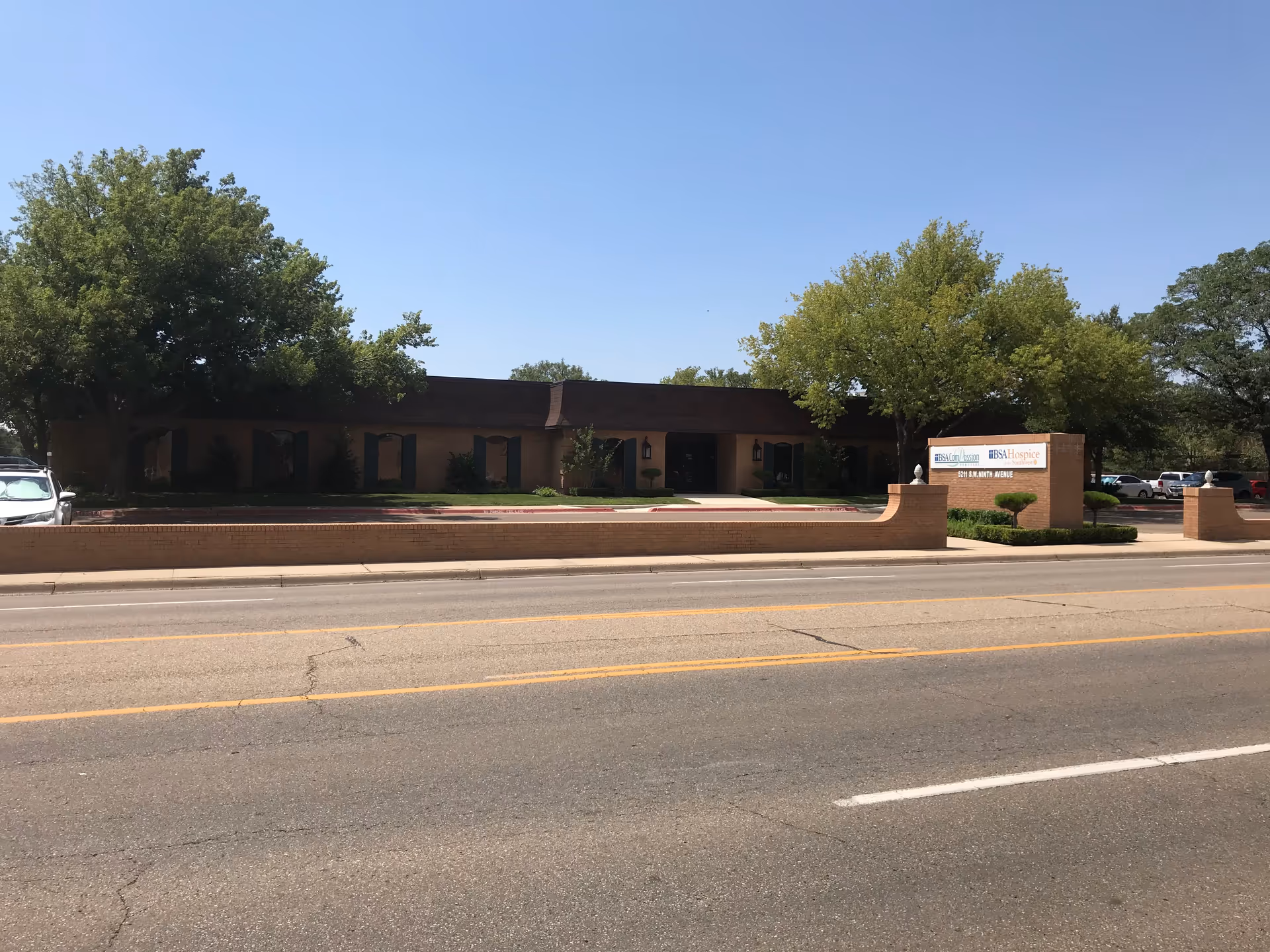 Exterior view of a single-story brick senior care building with a sign.