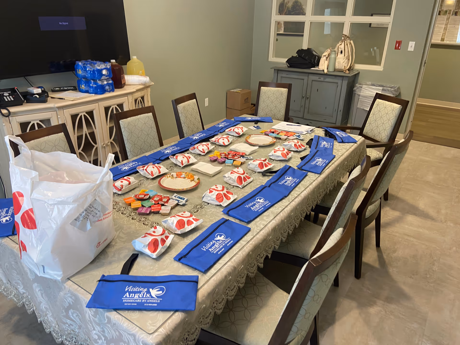 Long dining table set with blue Visiting Angels napkins and assorted place settings.