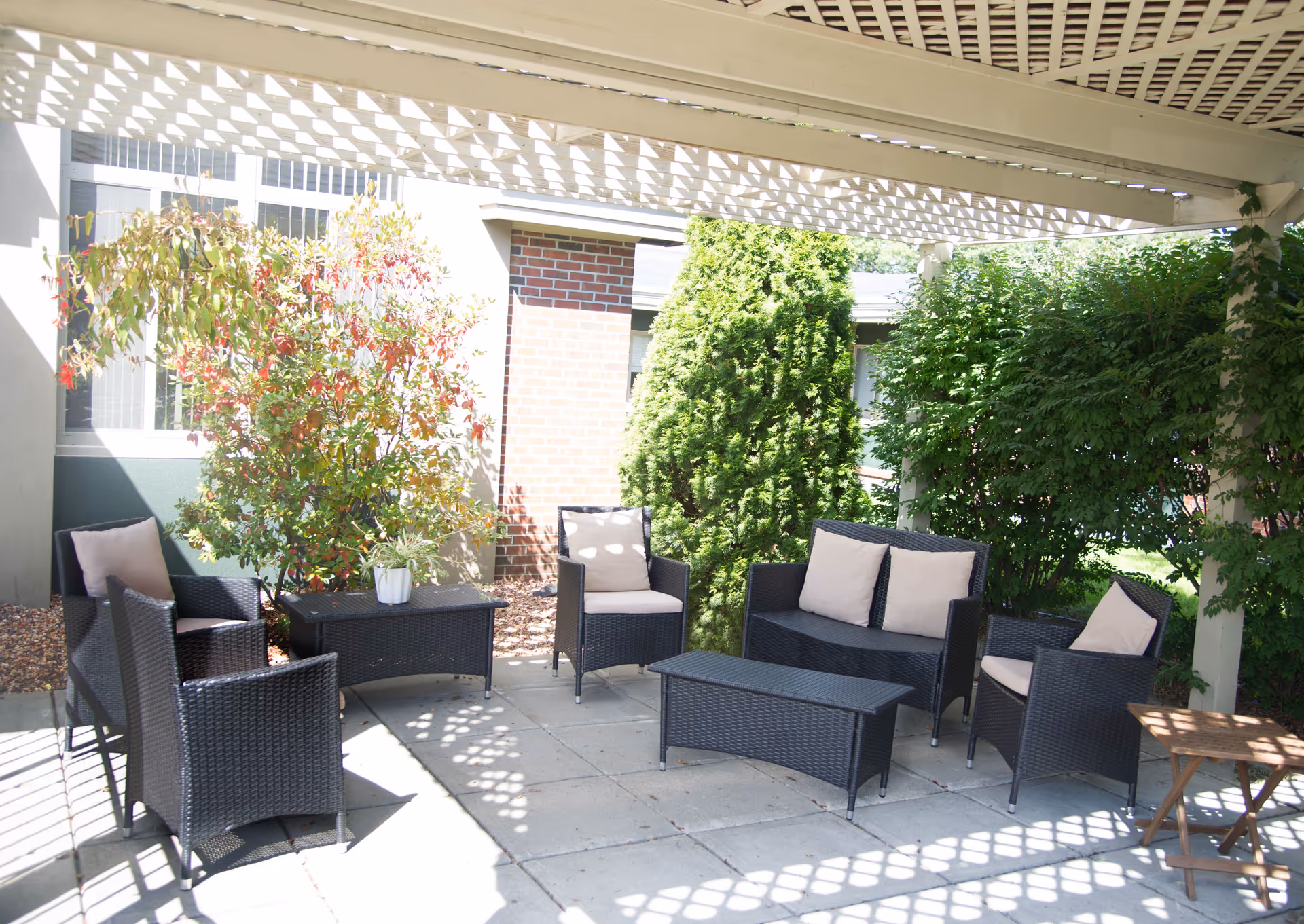 Outdoor patio seating with wicker furniture and cushions under a lattice canopy.