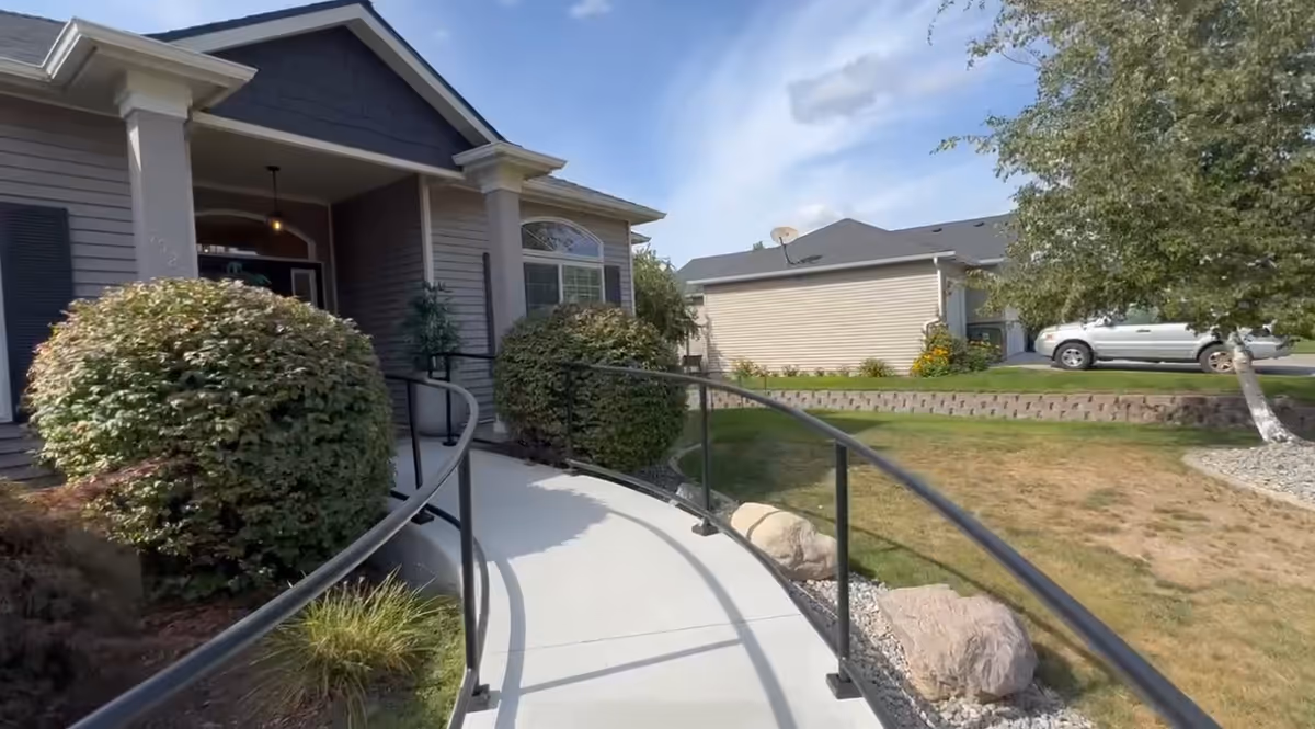 Curved ramp to the front entrance of a residential senior home with shrubs.
