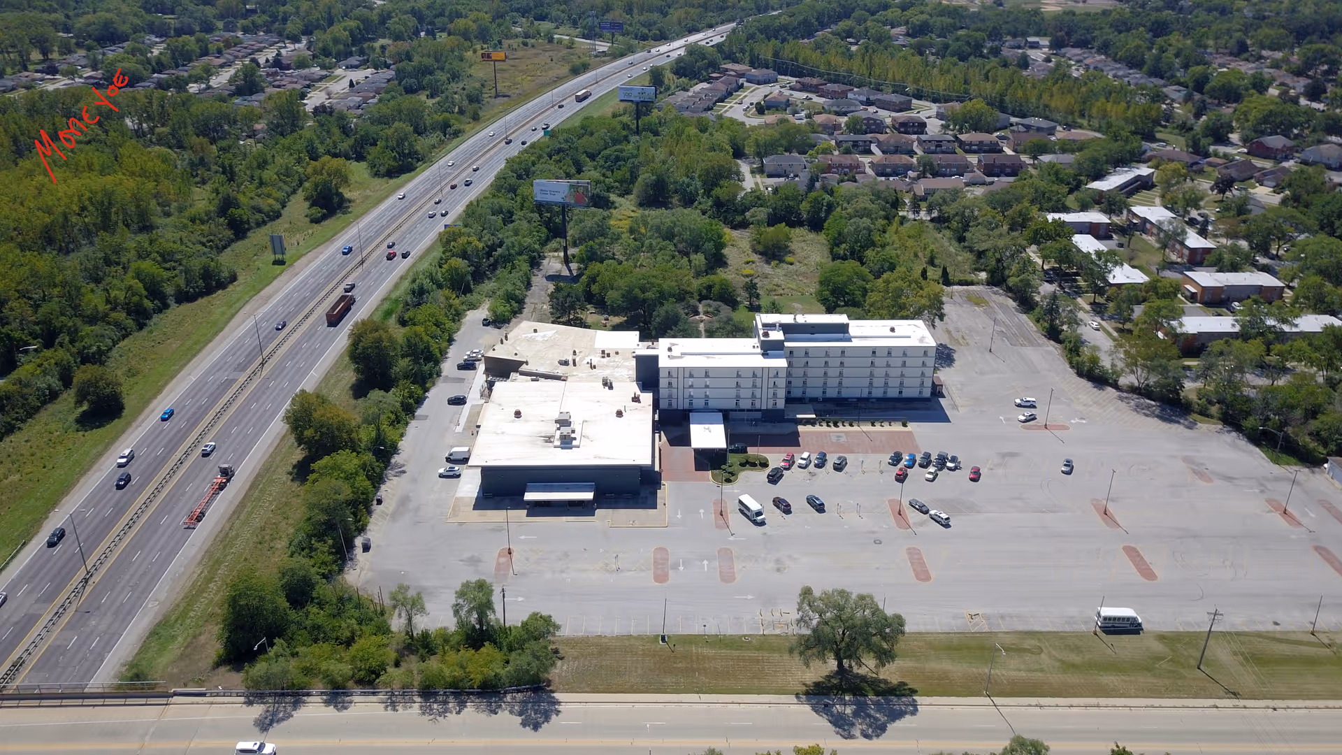 Aerial view of Royal Estates Assisted Living exterior with parking lot and nearby highway