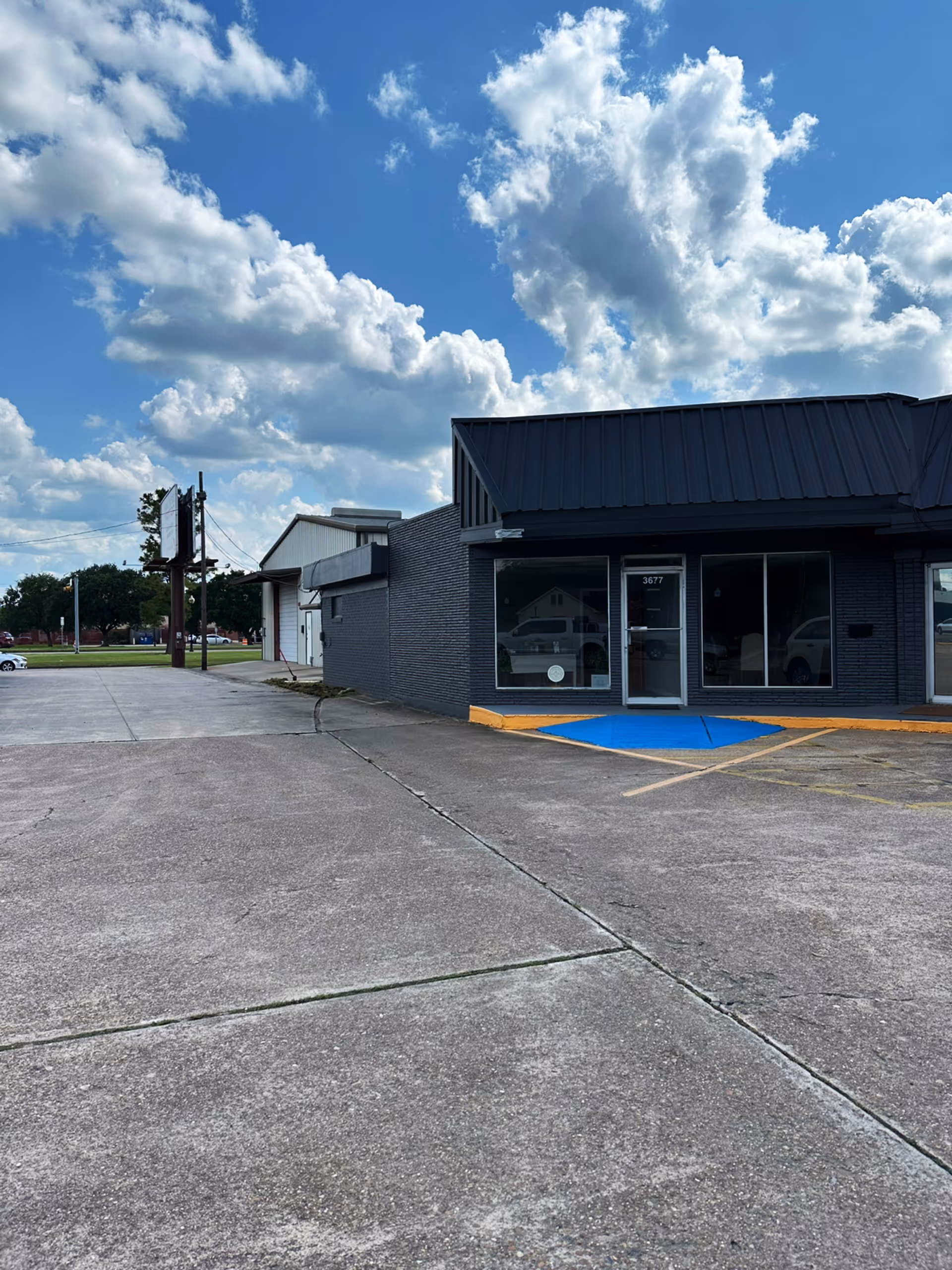 Exterior view of a gray brick building with glass storefront and accessible ramp.