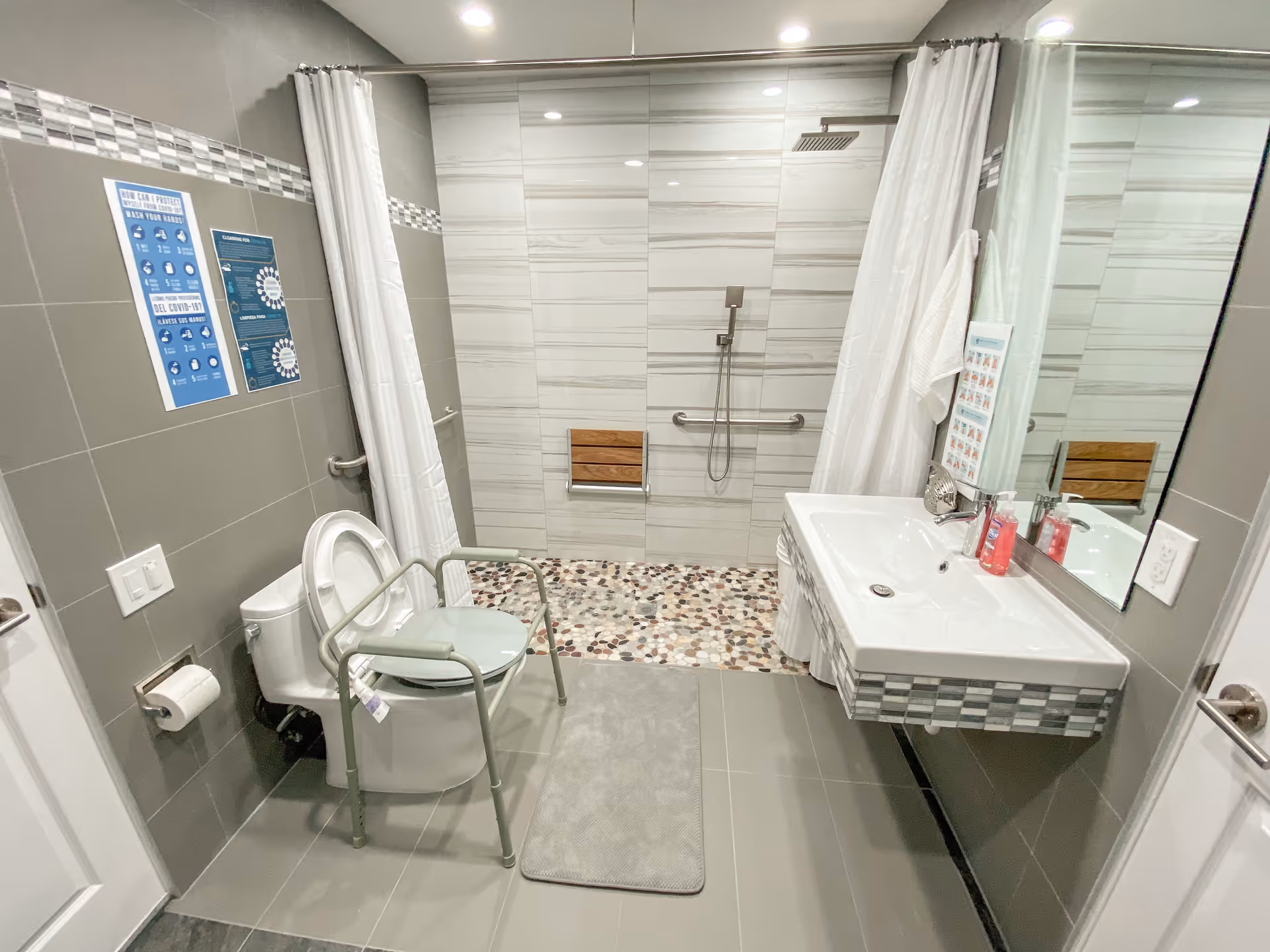 Accessible senior bathroom with shower, toilet, grab bars, sink, and safety features.