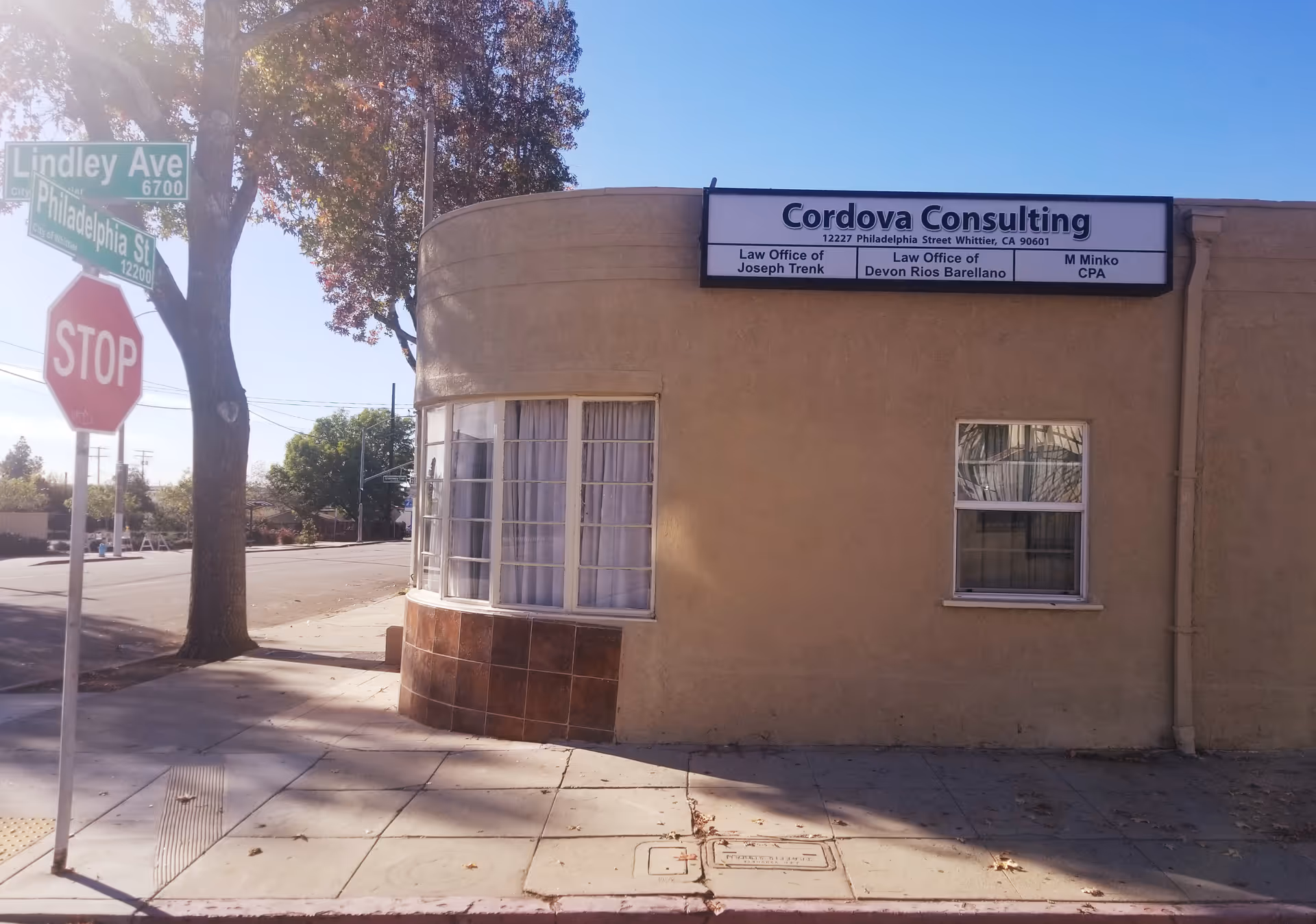 A beige stucco building on a street corner with Cordova Consulting sign and stop sign.
