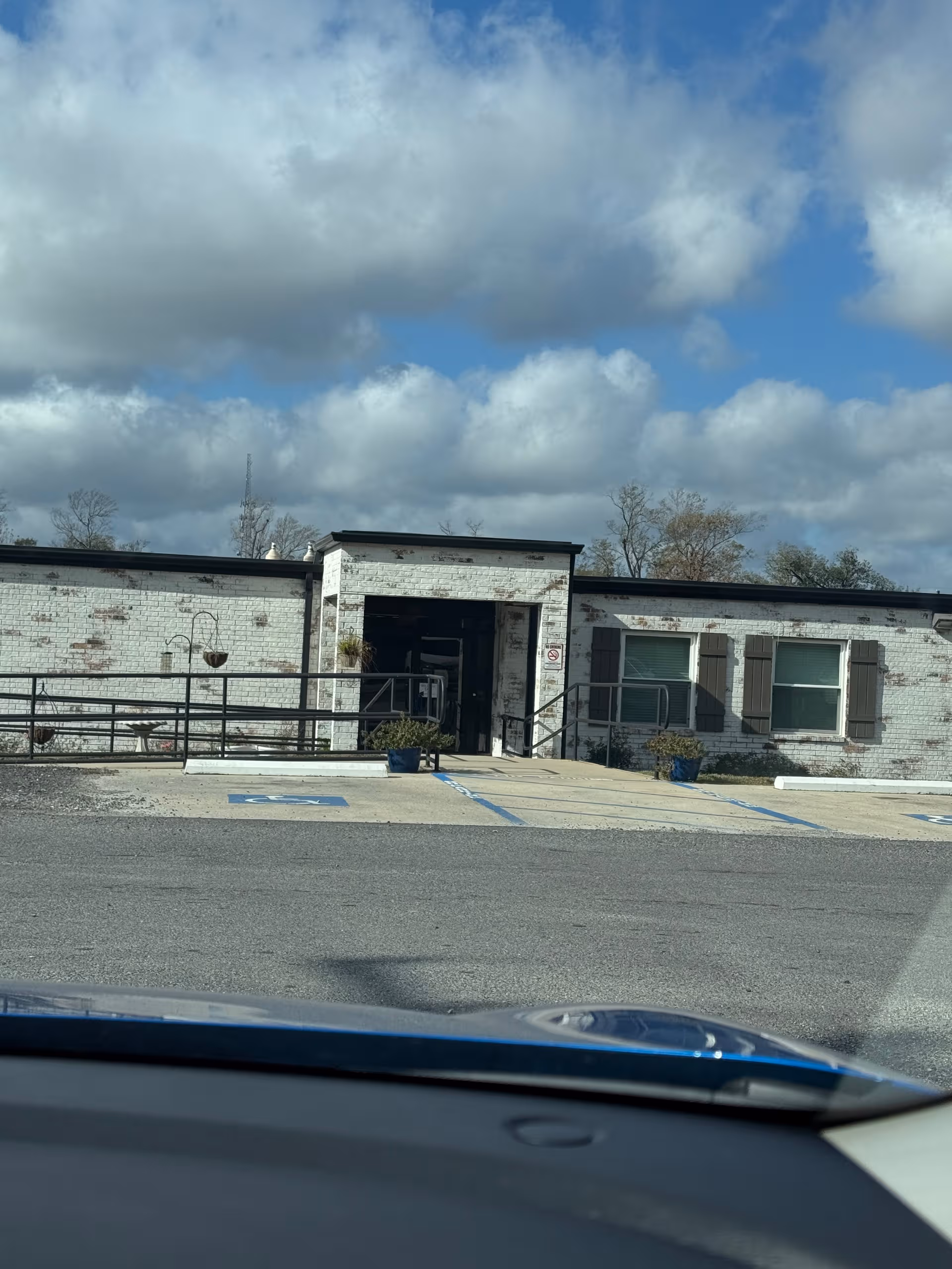Front view of a single-story brick nursing center with ramp and parking.