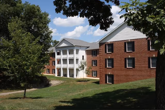 Exterior view of Twin Oaks Estate building with white entrance columns and trees.