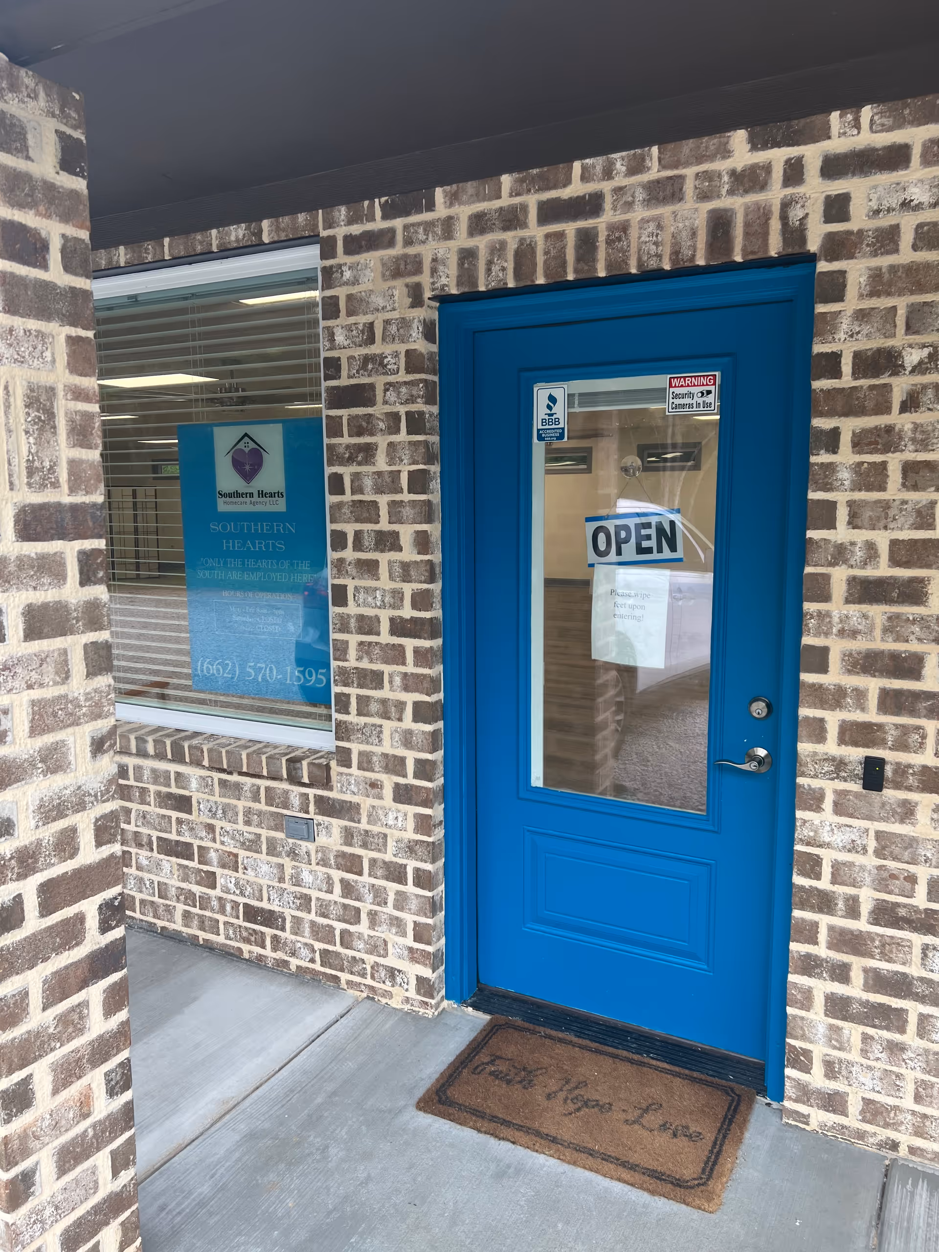 Brick exterior with a bright blue front door and a window sign for Southern Hearts.