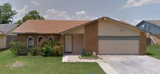 Front view of a single-story brick house with a two-car garage and green lawn.