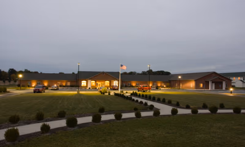 Exterior view of Putnam Heritage Assisted Living, a single-story building with flagpole and lights.