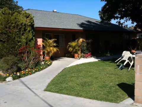 Front exterior of a single-story home with walkway, lawn, and potted plants.