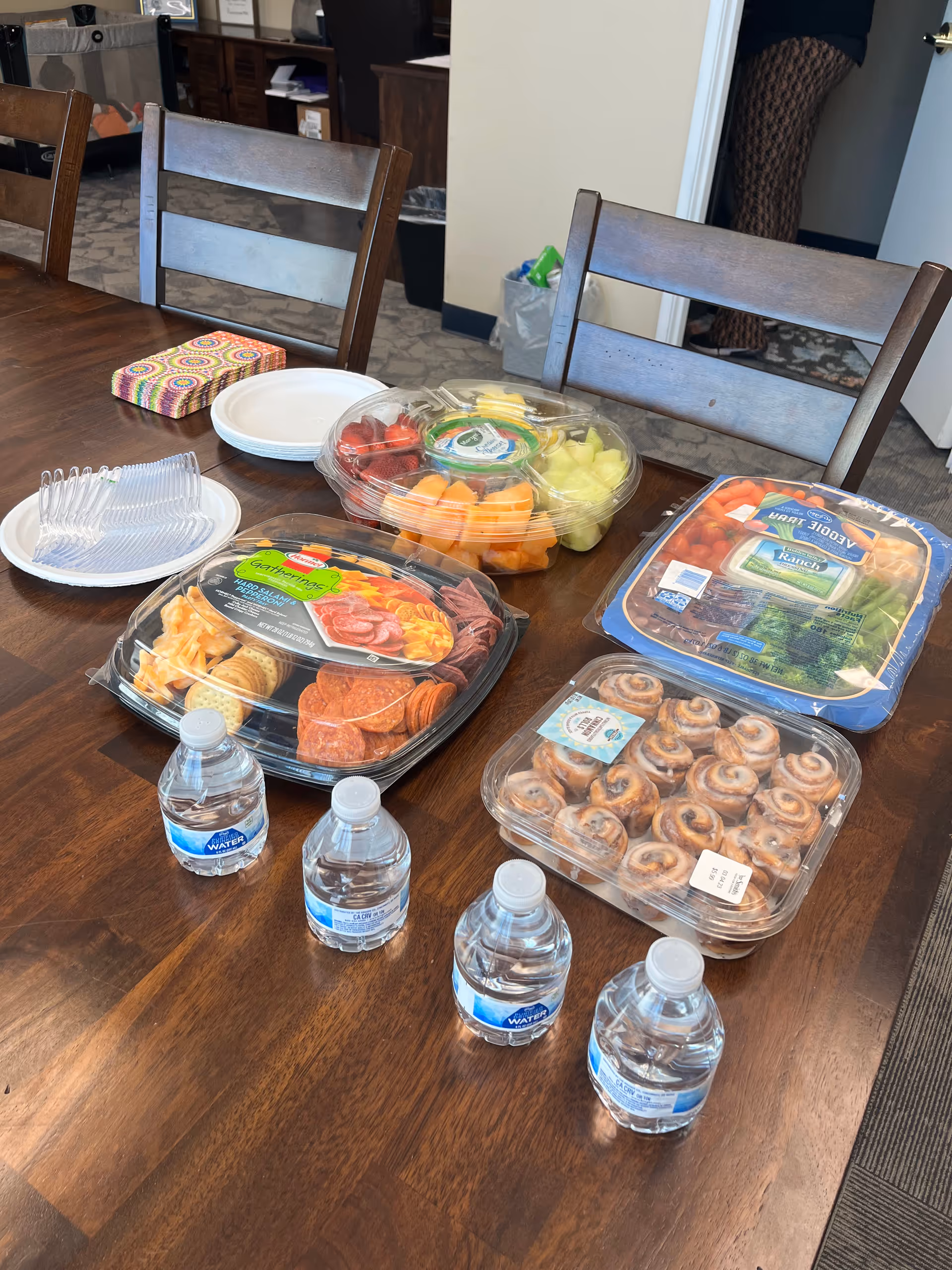 Assorted fruit, pastries, and snacks arranged on a dining table in a senior care facility.