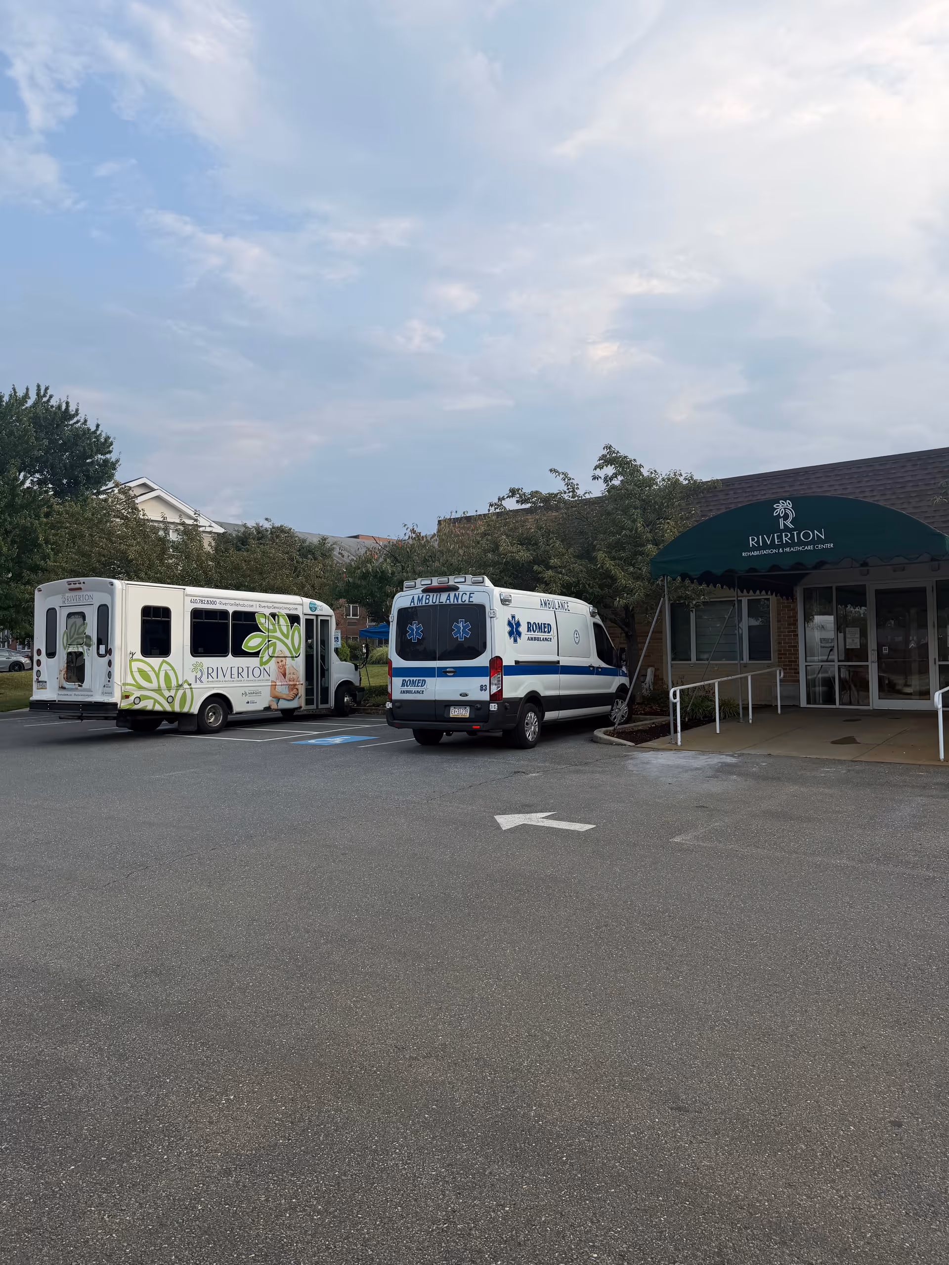 Ambulances and a bus parked in front of Riverton Enhanced Senior Living entrance.