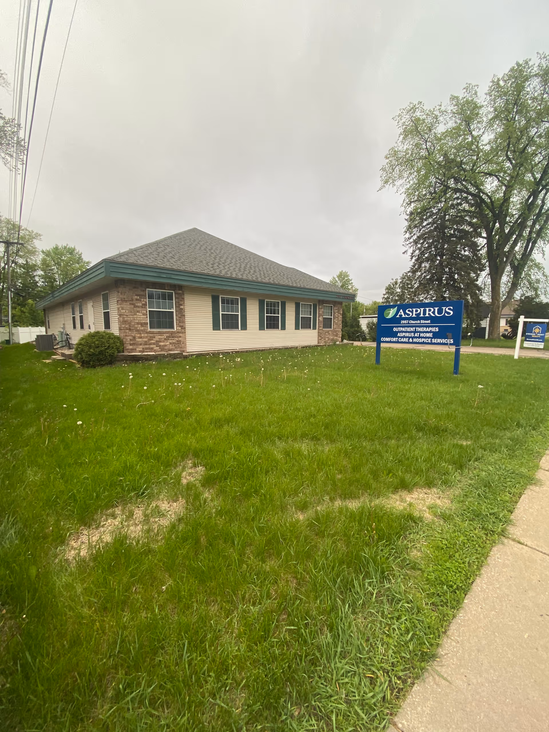 Single-story brick and siding facility with a blue Aspirus sign on a grassy front lawn.