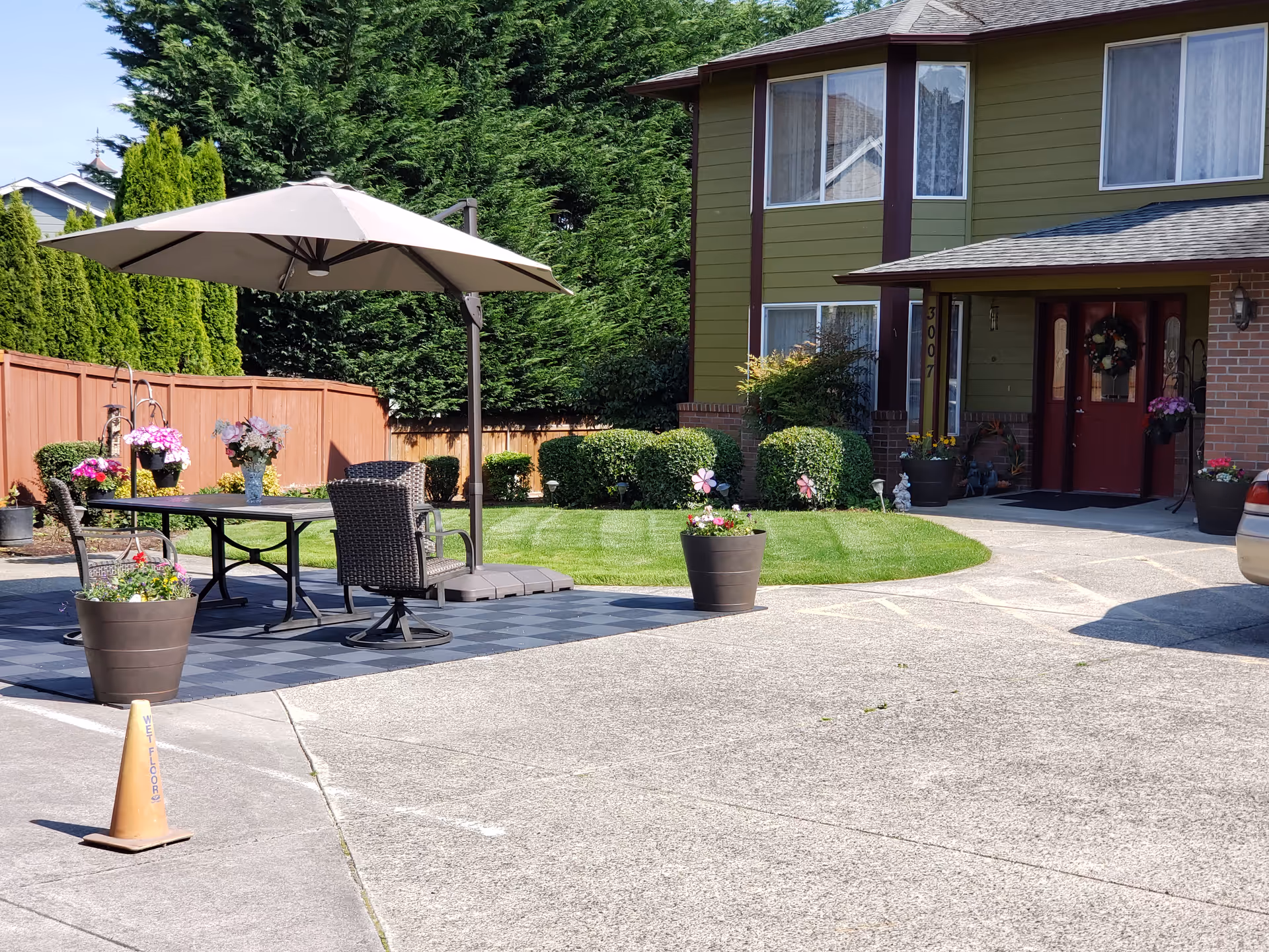 Exterior view of a green two-story senior facility with front entry and outdoor seating.